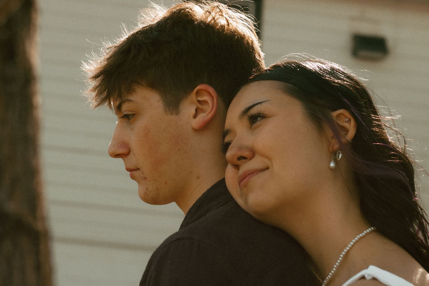 Silhouette of couple embracing during sunset against light background.