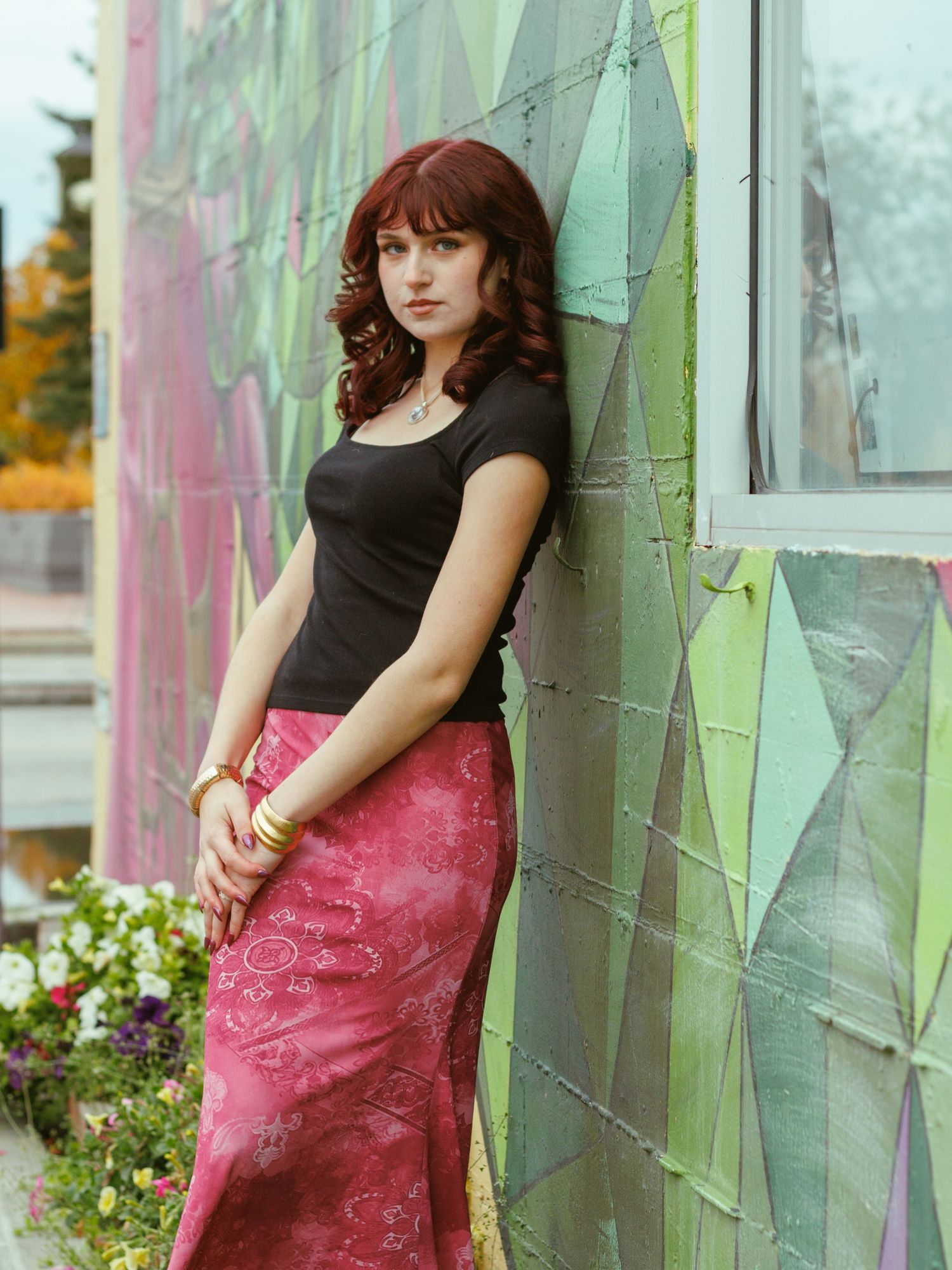 Person poses against geometric wall wearing black top and pink skirt.