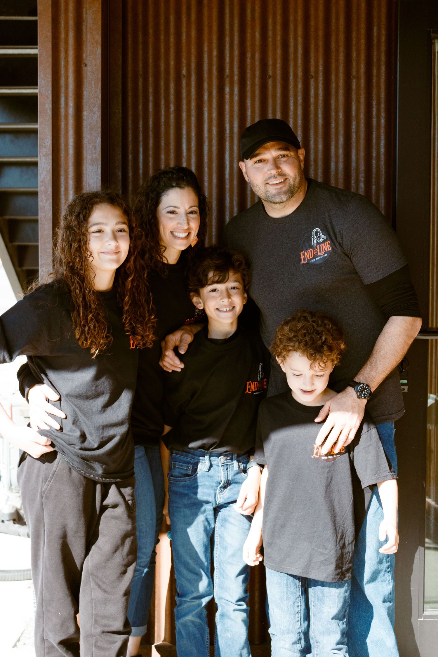 Group wearing matching dark shirts posing together outside a modern building.