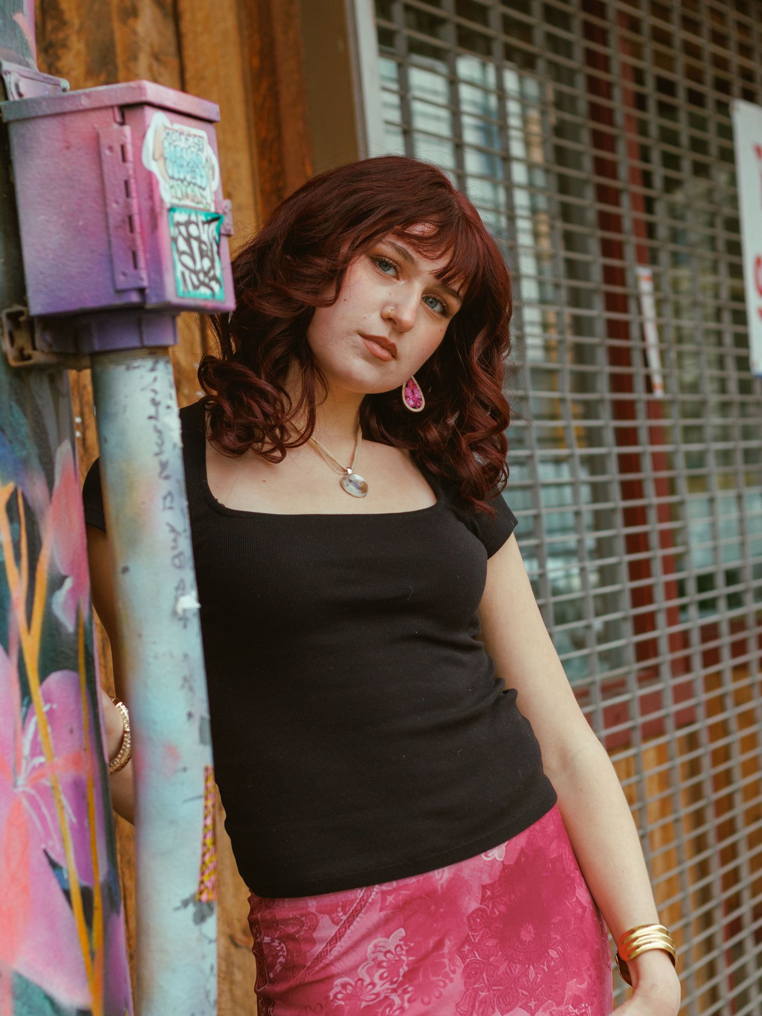 Woman in black top poses against colorful graffiti wall with vintage styling.