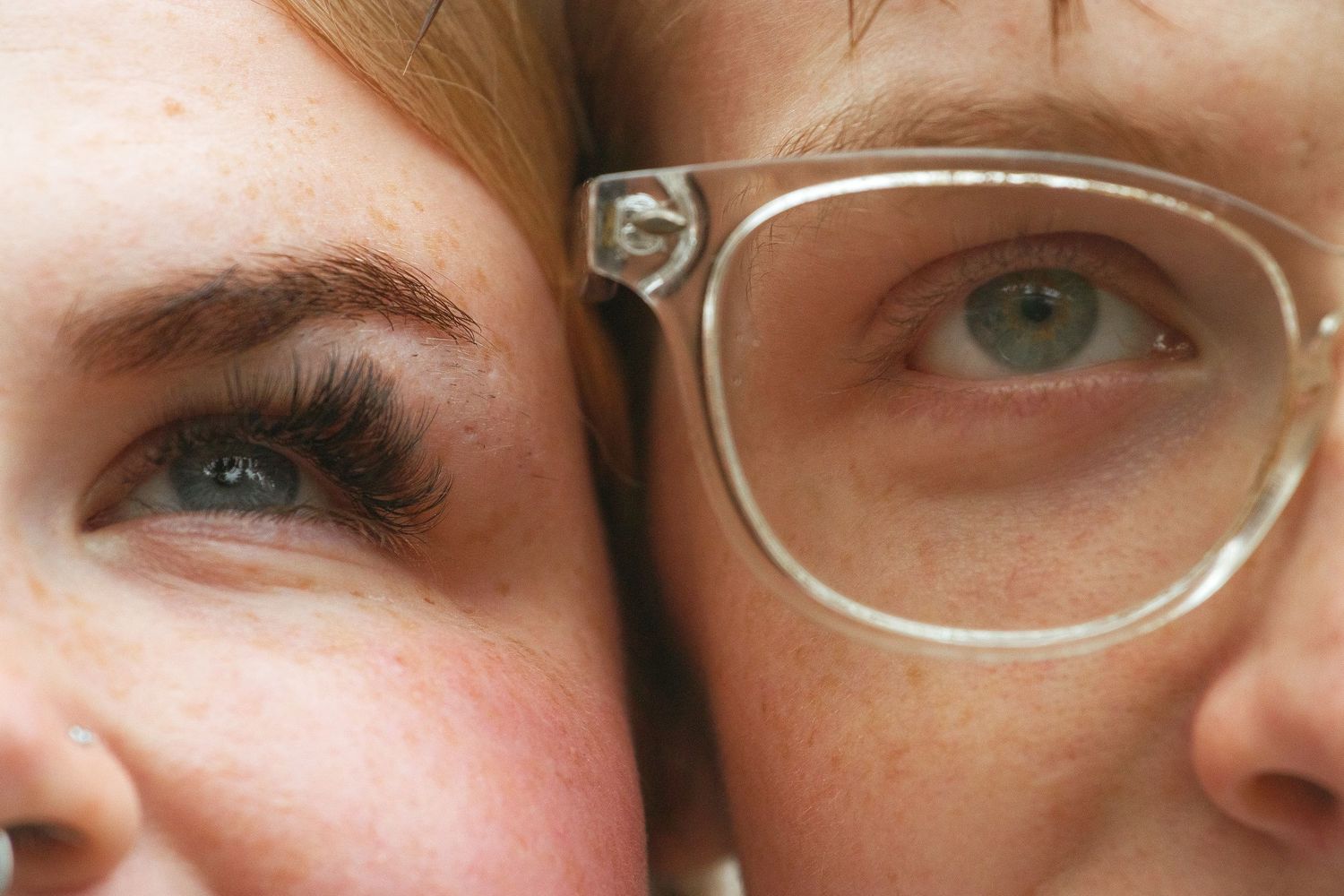 A close-up view of several eyes in a row, some wearing glasses and others showing natural green irises.