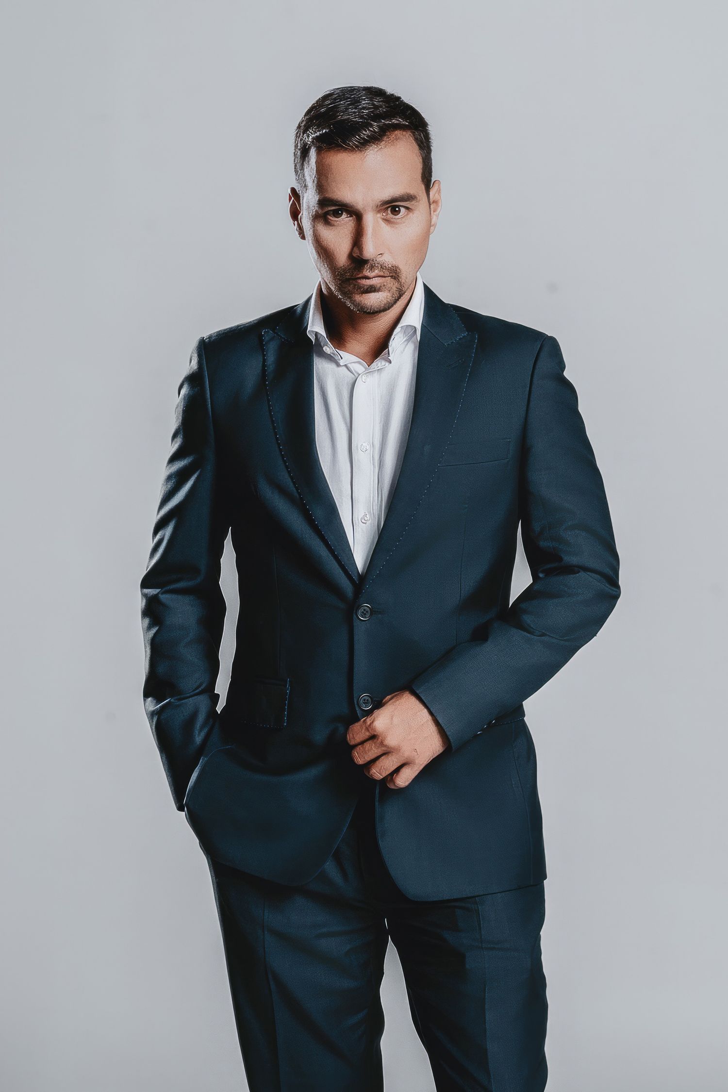 Studio fashion shot of man in tailored navy business suit.