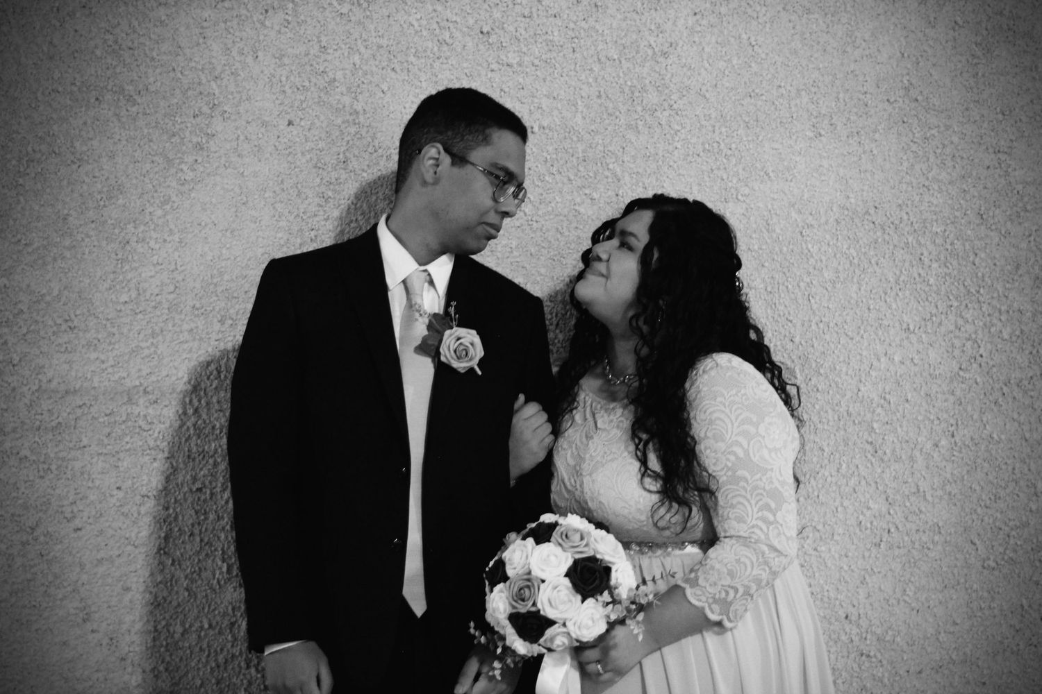 A romantic black and white wedding photo with couple exchanging loving glances.