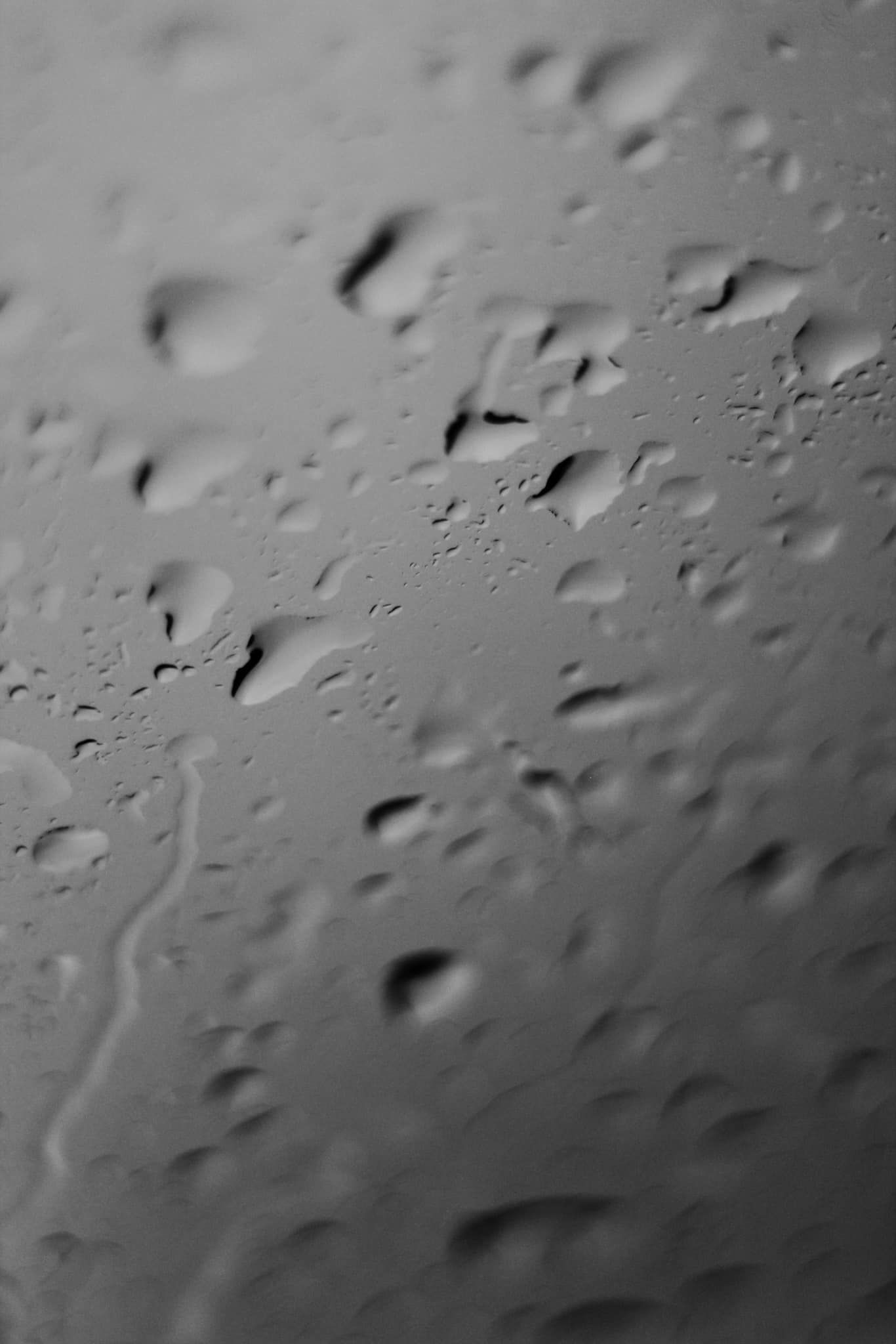 Abstract black and white photograph of water droplets on glass surface.