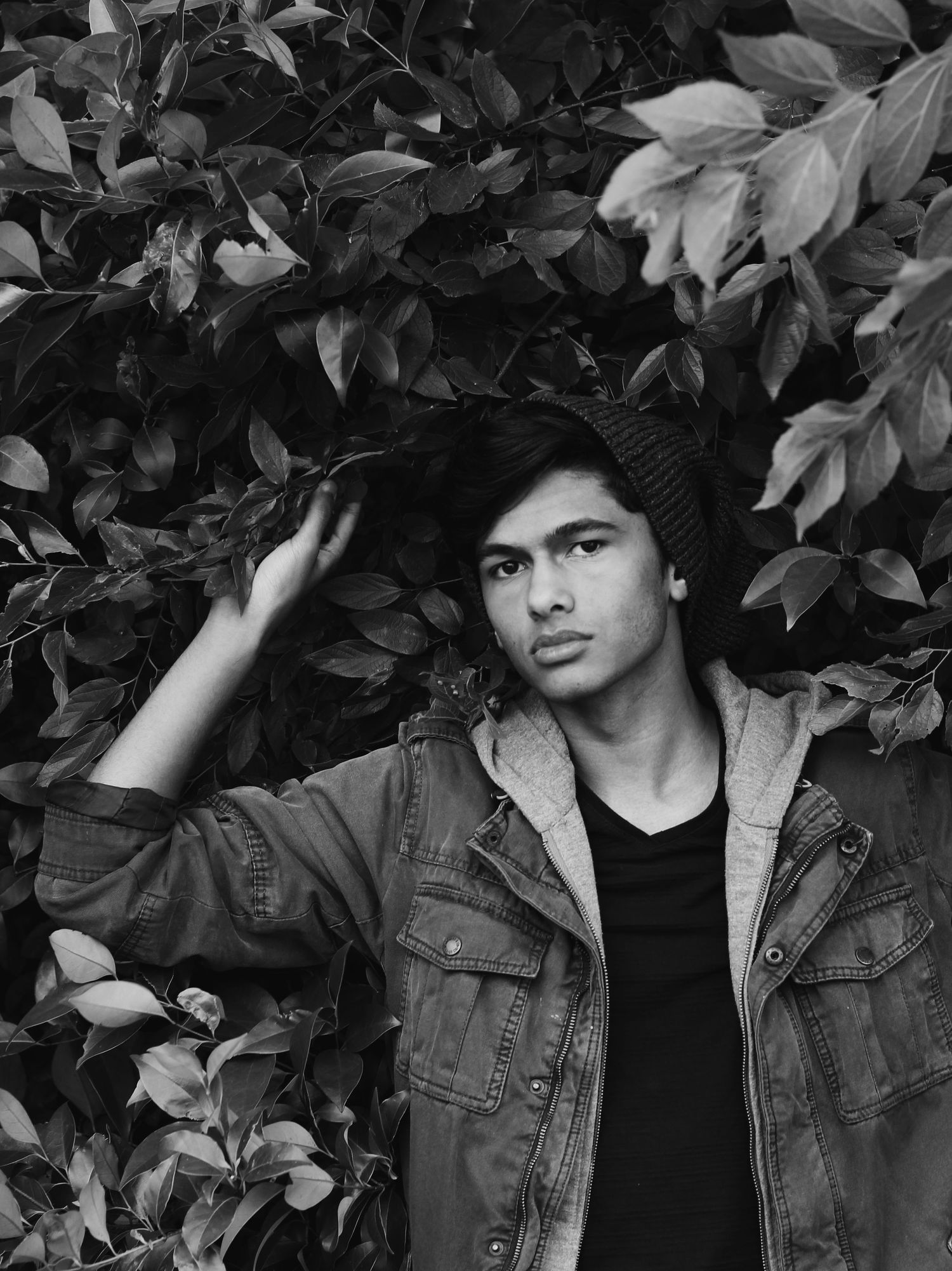 Artistic black and white portrait in front of leaves and foliage.