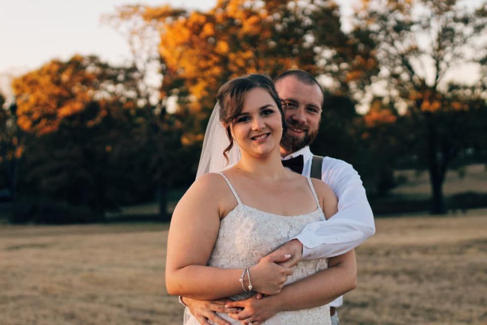 Newlywed couple embracing during sunset photoshoot in outdoor setting.