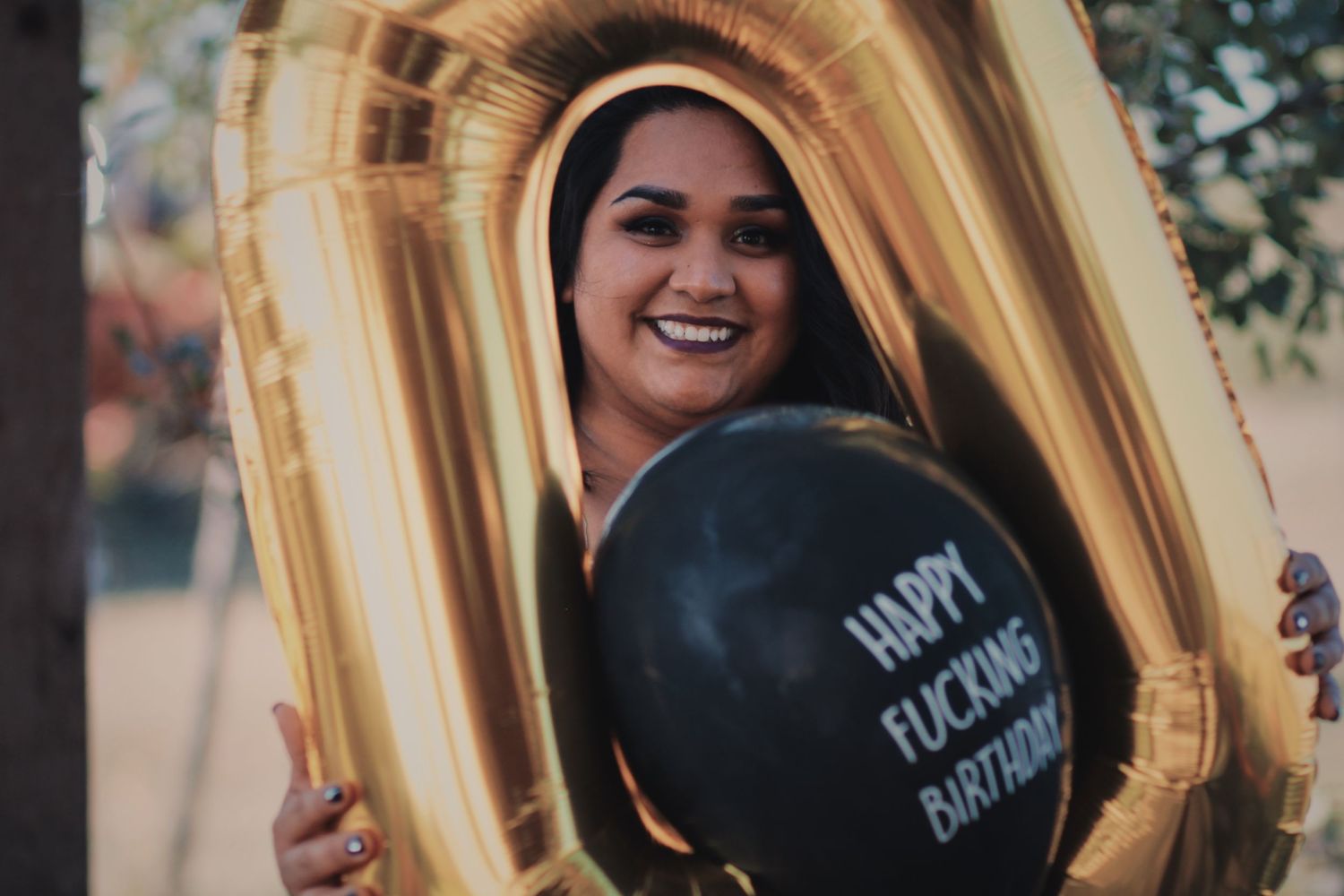 A celebratory photo with gold balloon decorations and a humorous black balloon.