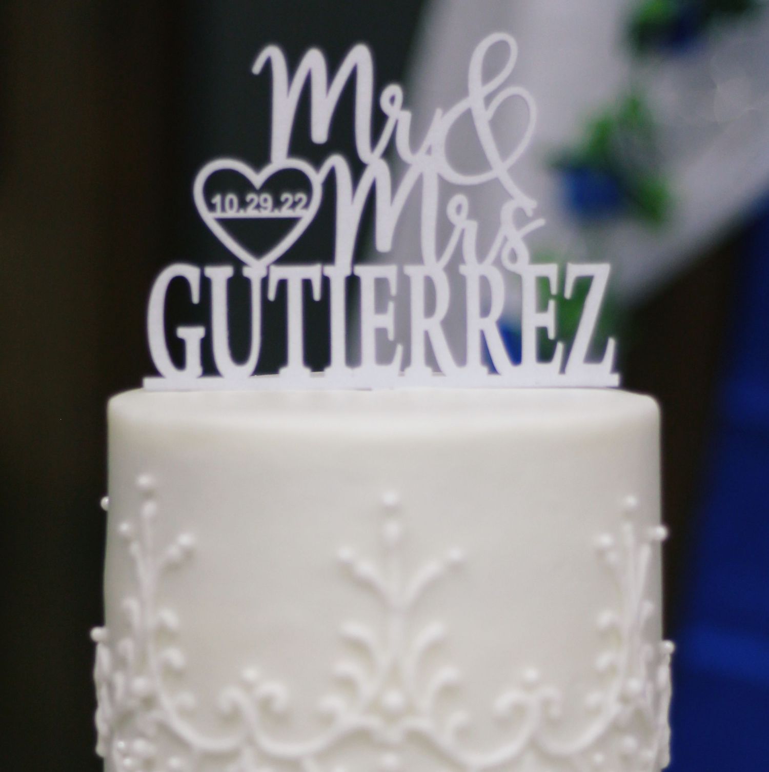 White wedding cake topper displaying 'Mr & Mrs Gutierrez' with a heart shape and date detail.