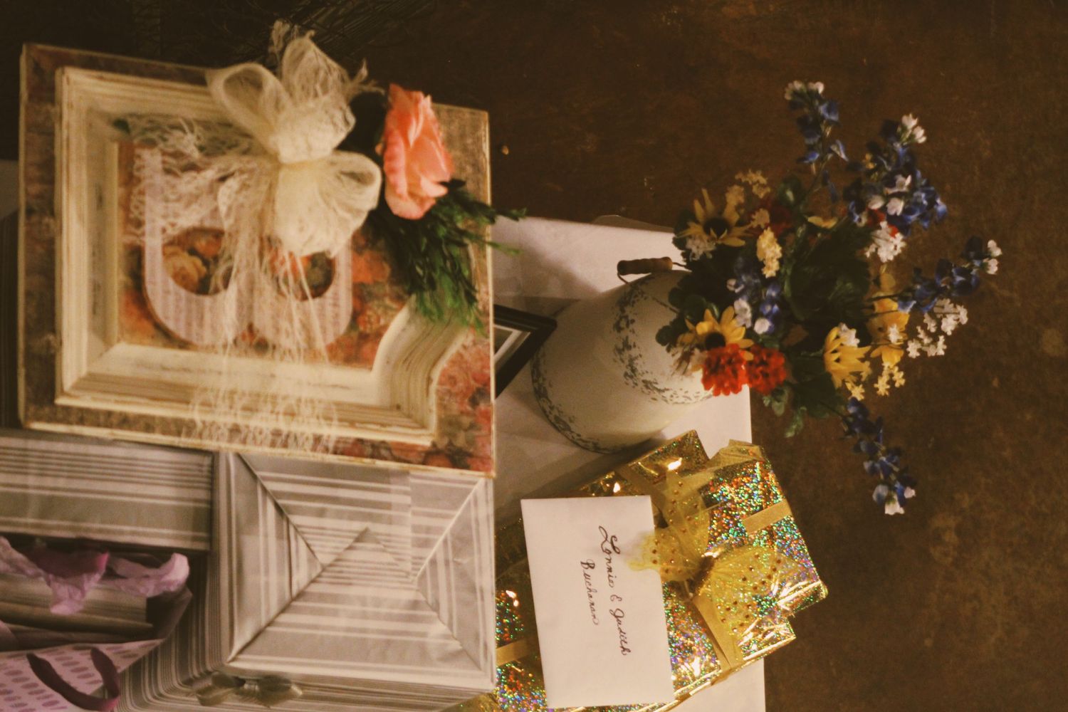 Vintage styled still life with flowers and papers on a dark surface.