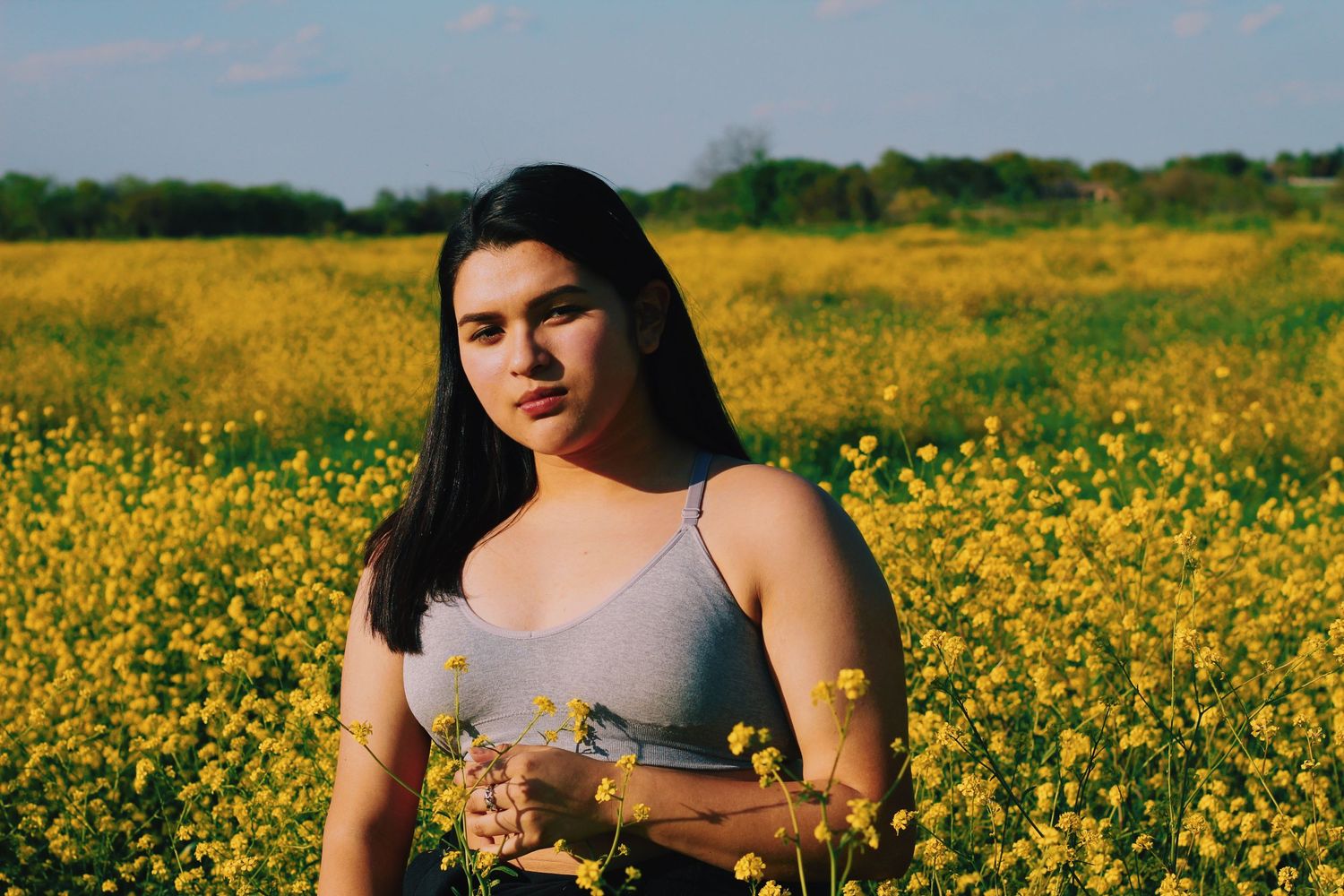 Portrait in a field of bright yellow wildflowers on a sunny day.