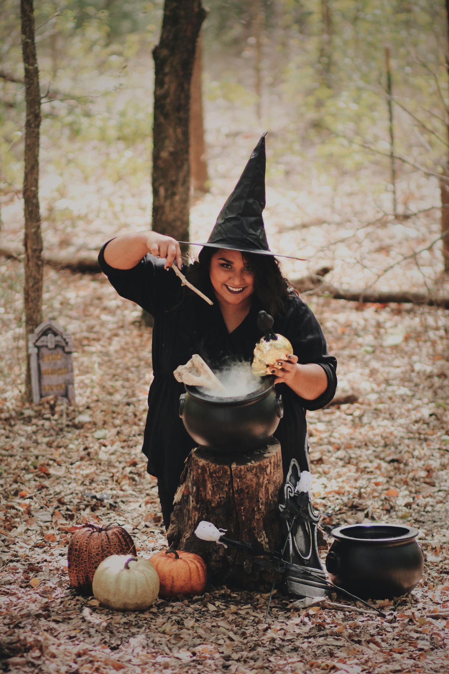 A witch-themed photo with someone stirring a cauldron surrounded by pumpkins and Halloween decorations.