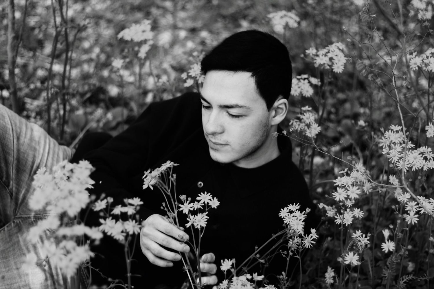Black and white portrait among delicate white wildflowers in a natural outdoor setting.