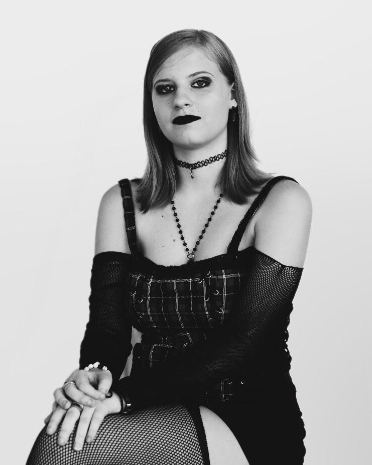 Gothic style portrait featuring dark makeup, fishnet sleeves, and beaded necklaces in black and white.