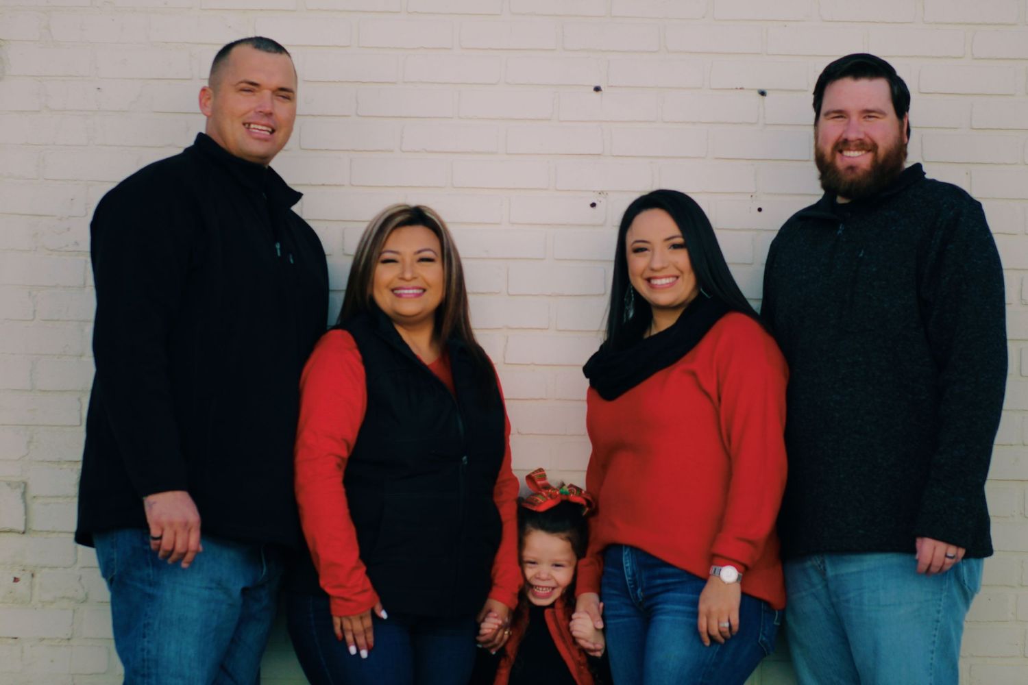 Holiday family portrait with five people wearing coordinating red and black outfits.