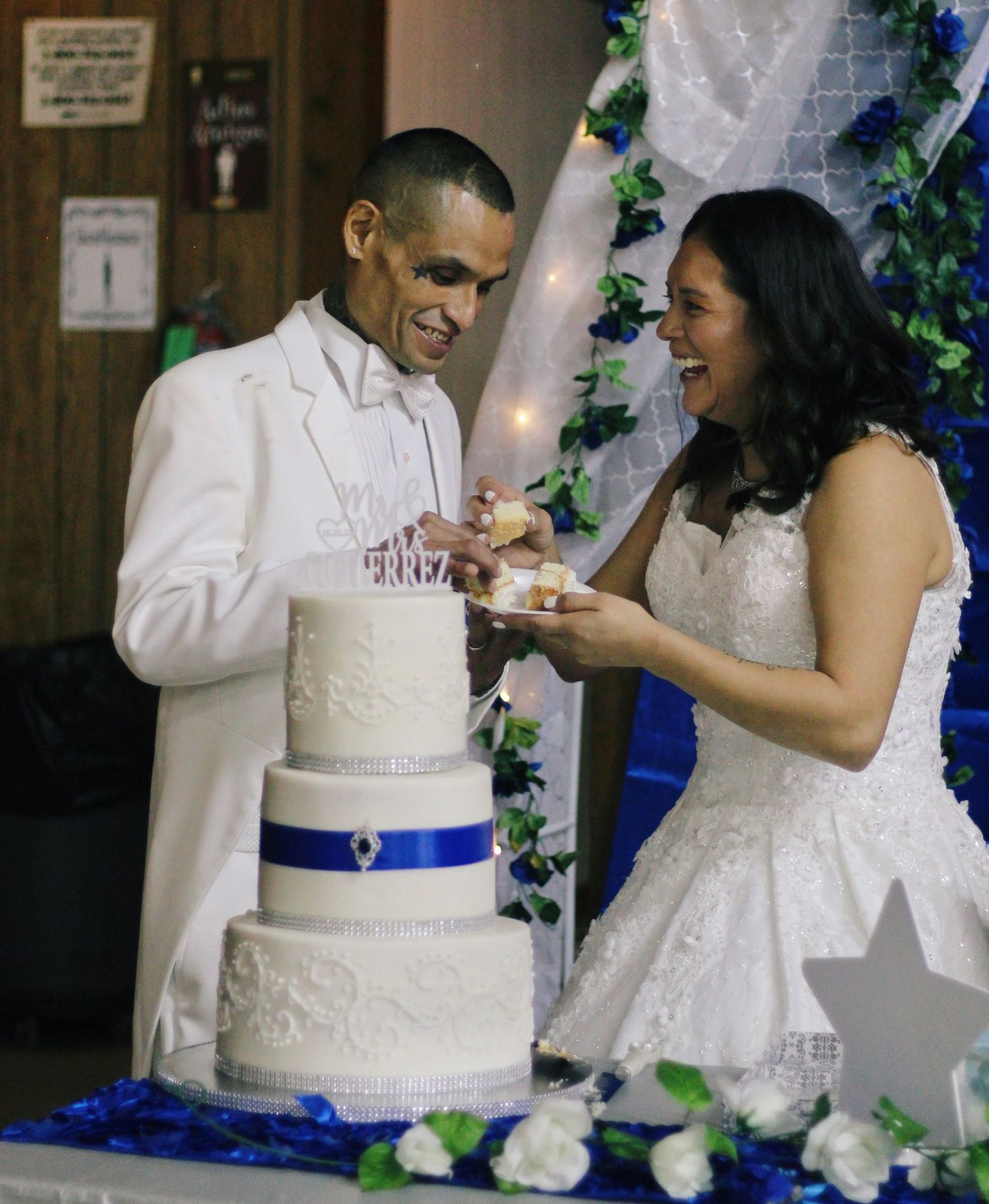 Wedding couple sharing a moment while cutting their elegant white and blue tiered cake.