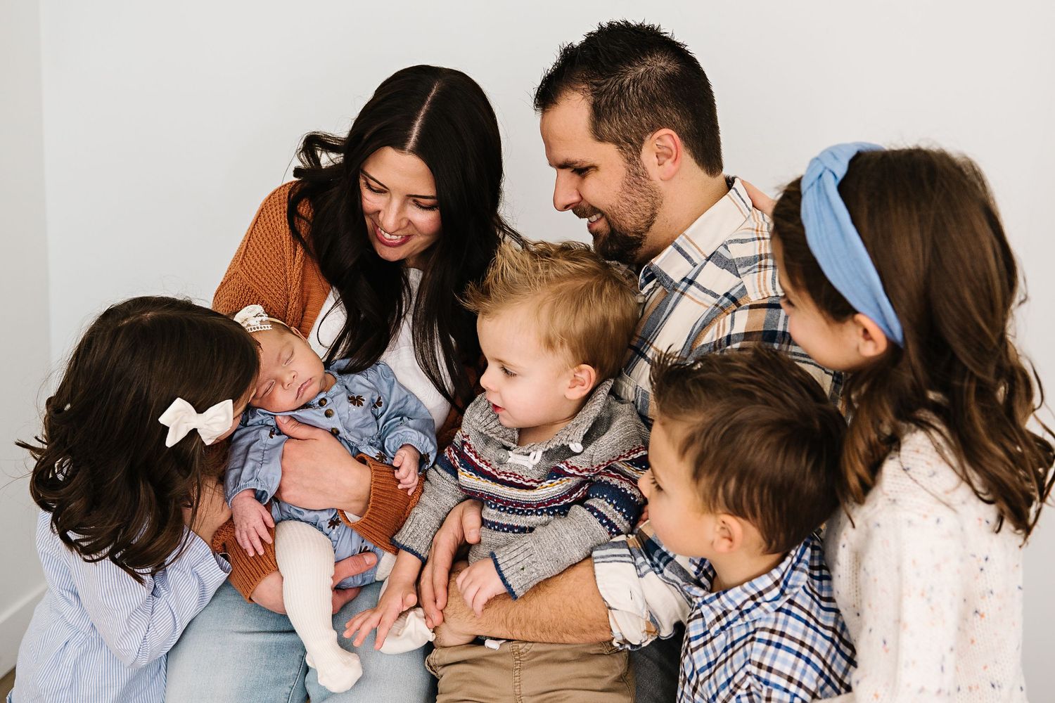 Indoor family portrait features tender moments between family members in coordinated outfits.
