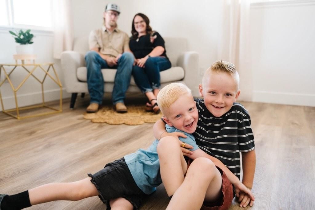 A family relaxes together in their modern living room with hardwood floors and white walls.