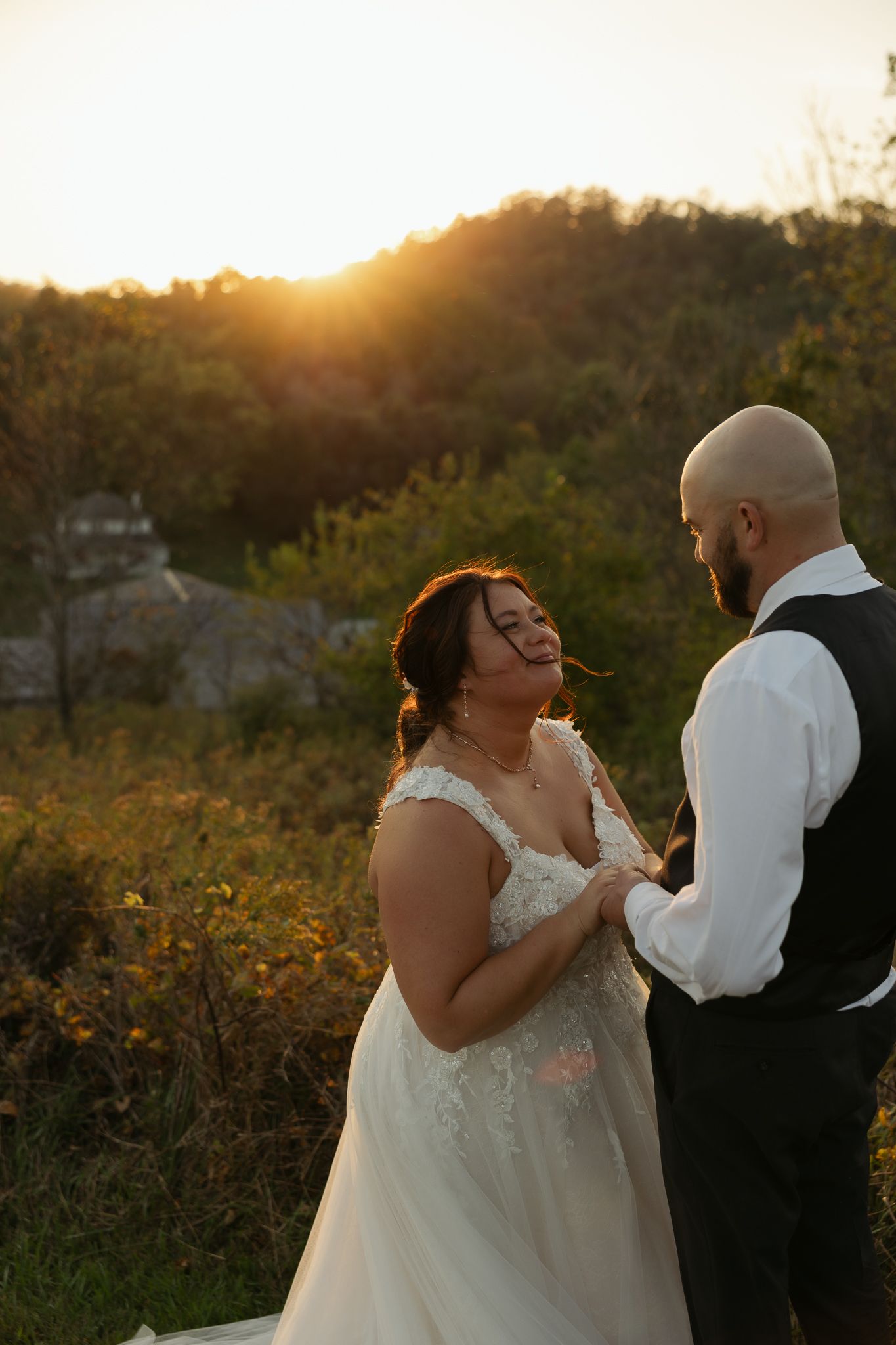 Wedding couple embraces during golden hour photography session in a natural outdoor setting.