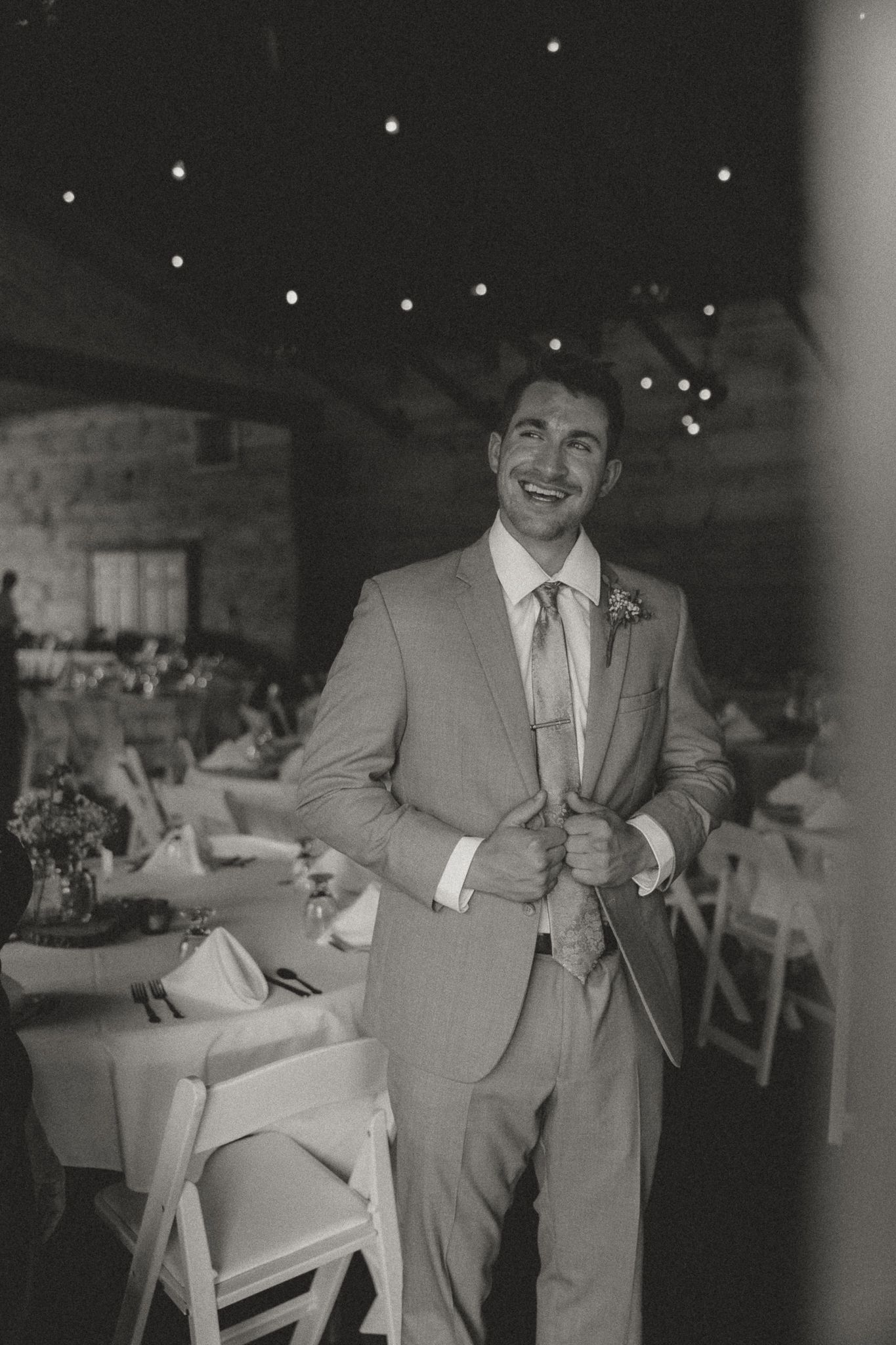 People in formal attire dancing and celebrating at an indoor reception with string lights.