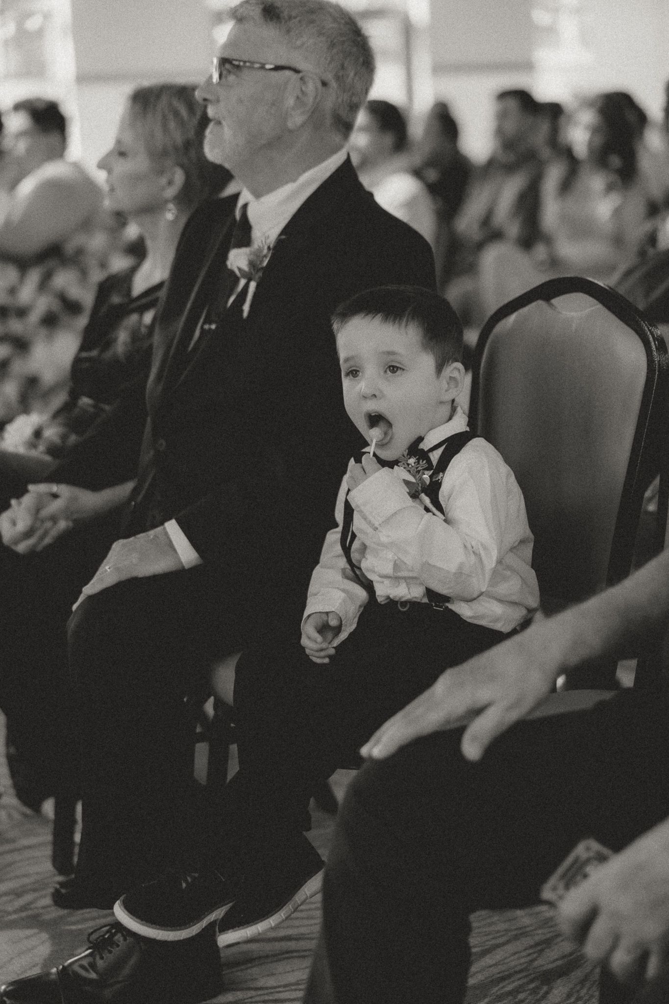 Wedding ceremony guests watch attentively in black and white photography.