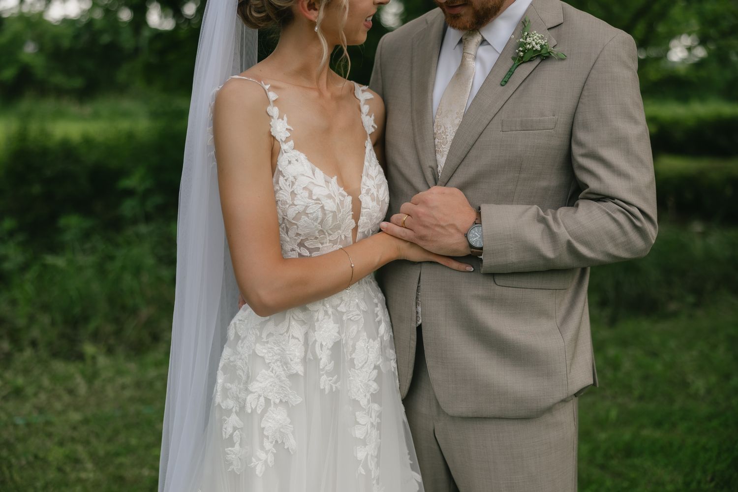 A romantic outdoor wedding portrait with the couple embracing against lush greenery.
