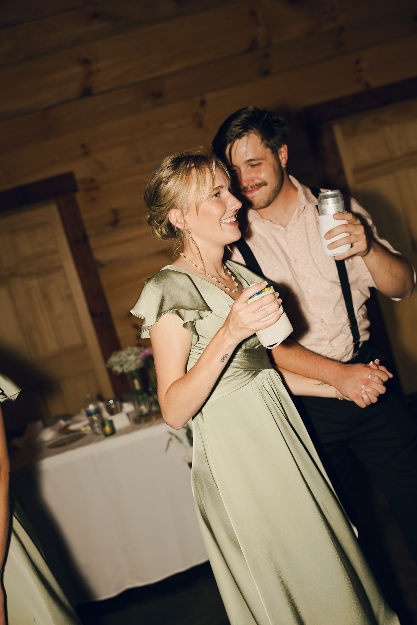 A couple sharing an intimate dance moment at a wedding reception in a rustic wooden venue.