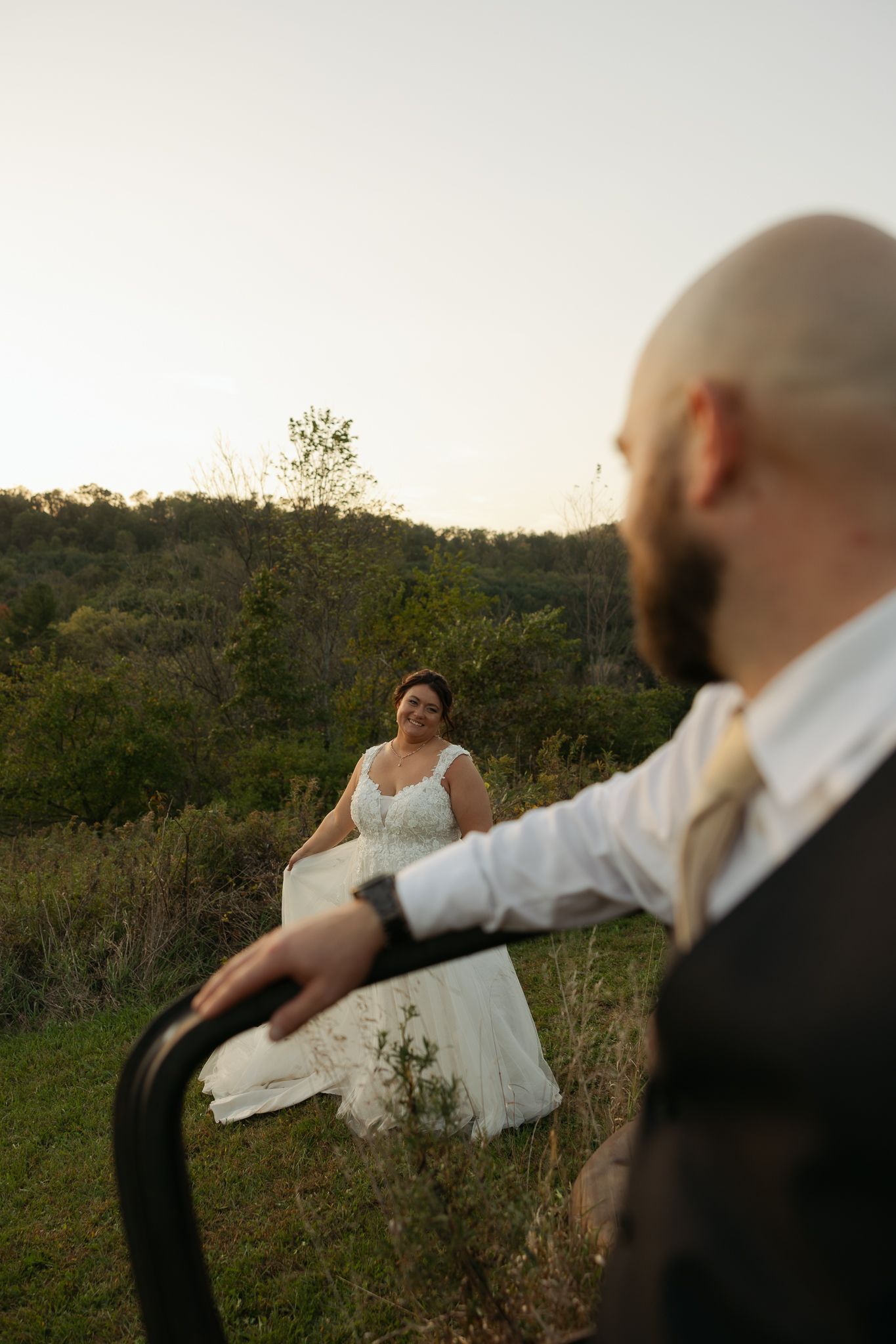 Wedding couple dances playfully in an outdoor field at dusk.
