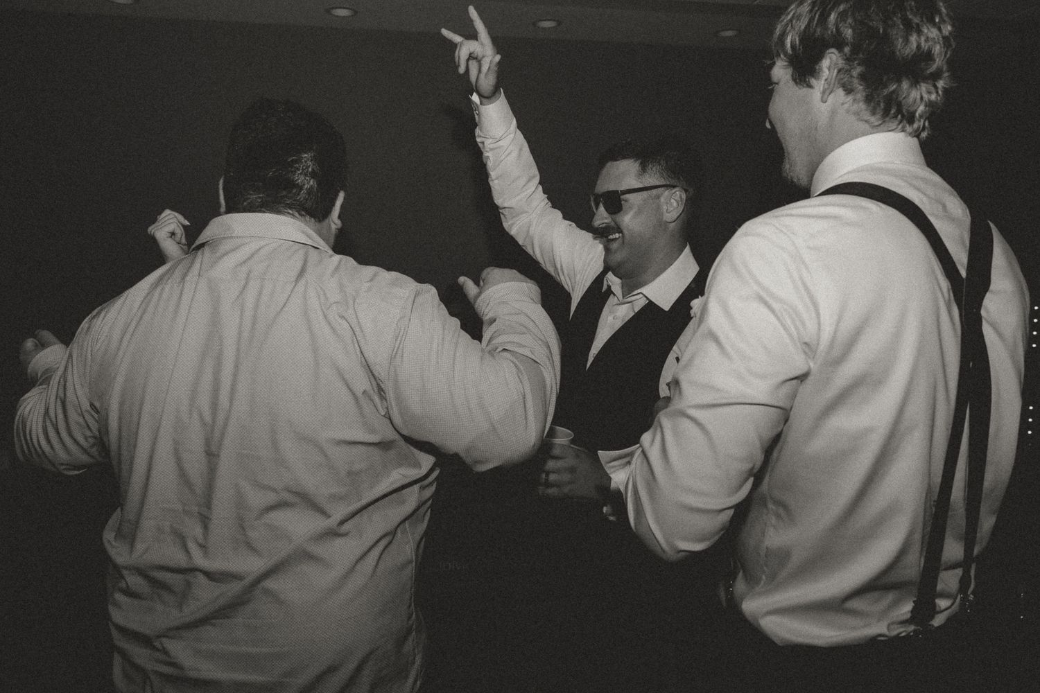 A black and white photo shows guests dancing and celebrating at a party.