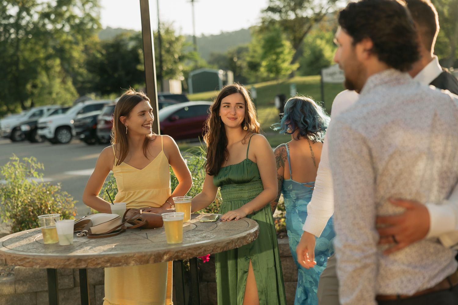 Wedding guests enjoying drinks and conversation on an outdoor patio during sunset.
