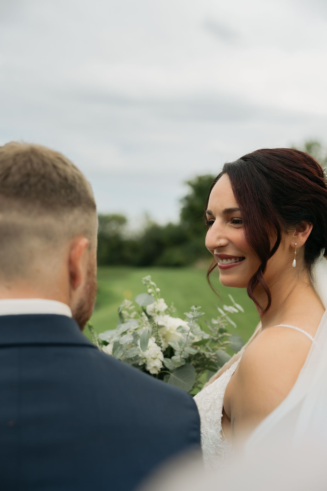 Close-up wedding portrait showing bouquet details against an overcast sky.