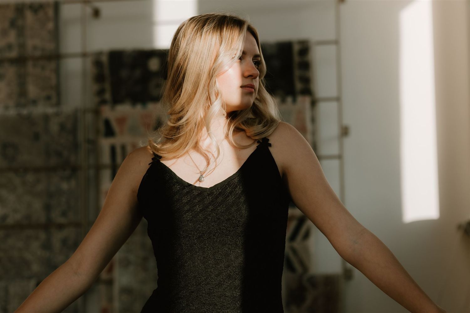 Woman in dark dress dancing joyfully in sunlit room.