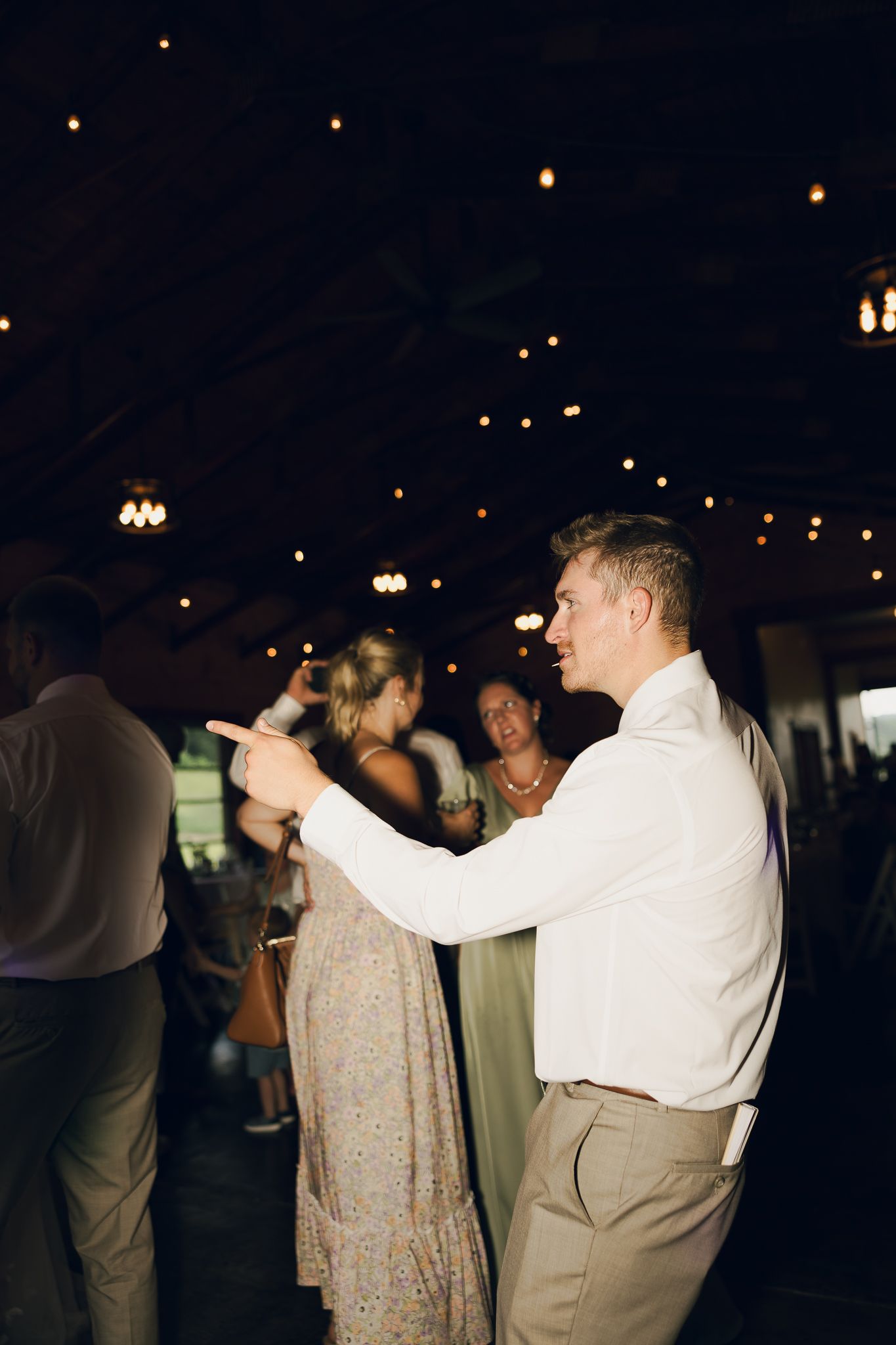 Guests dancing at a dimly lit wedding reception with string lights overhead.
