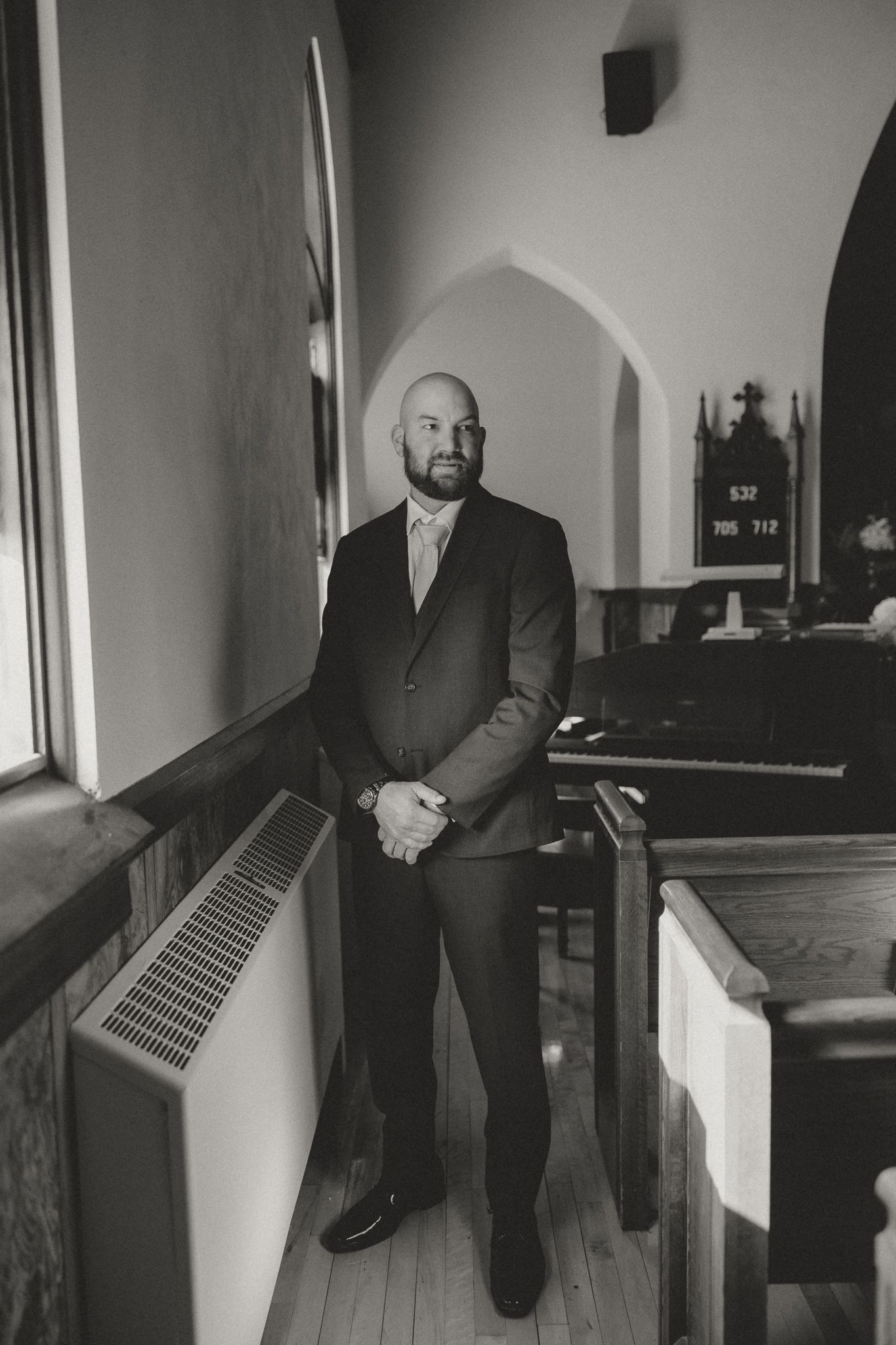 Person in formal attire standing in church hallway captured in black and white.