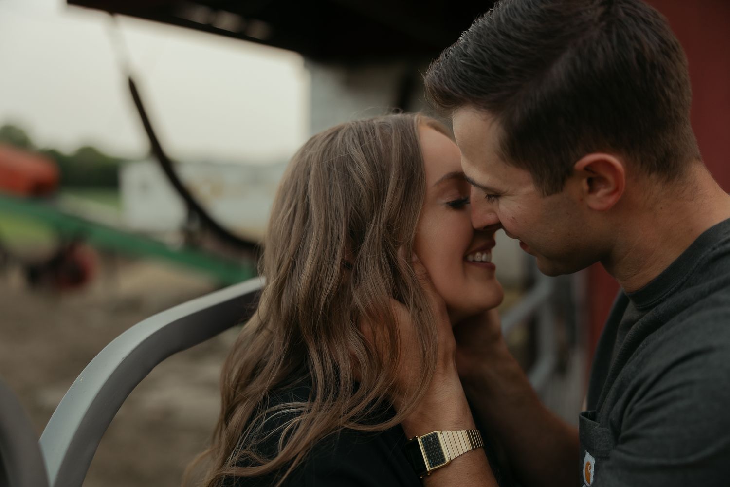 An intimate close-up of a couple sharing a tender moment against a rustic background.