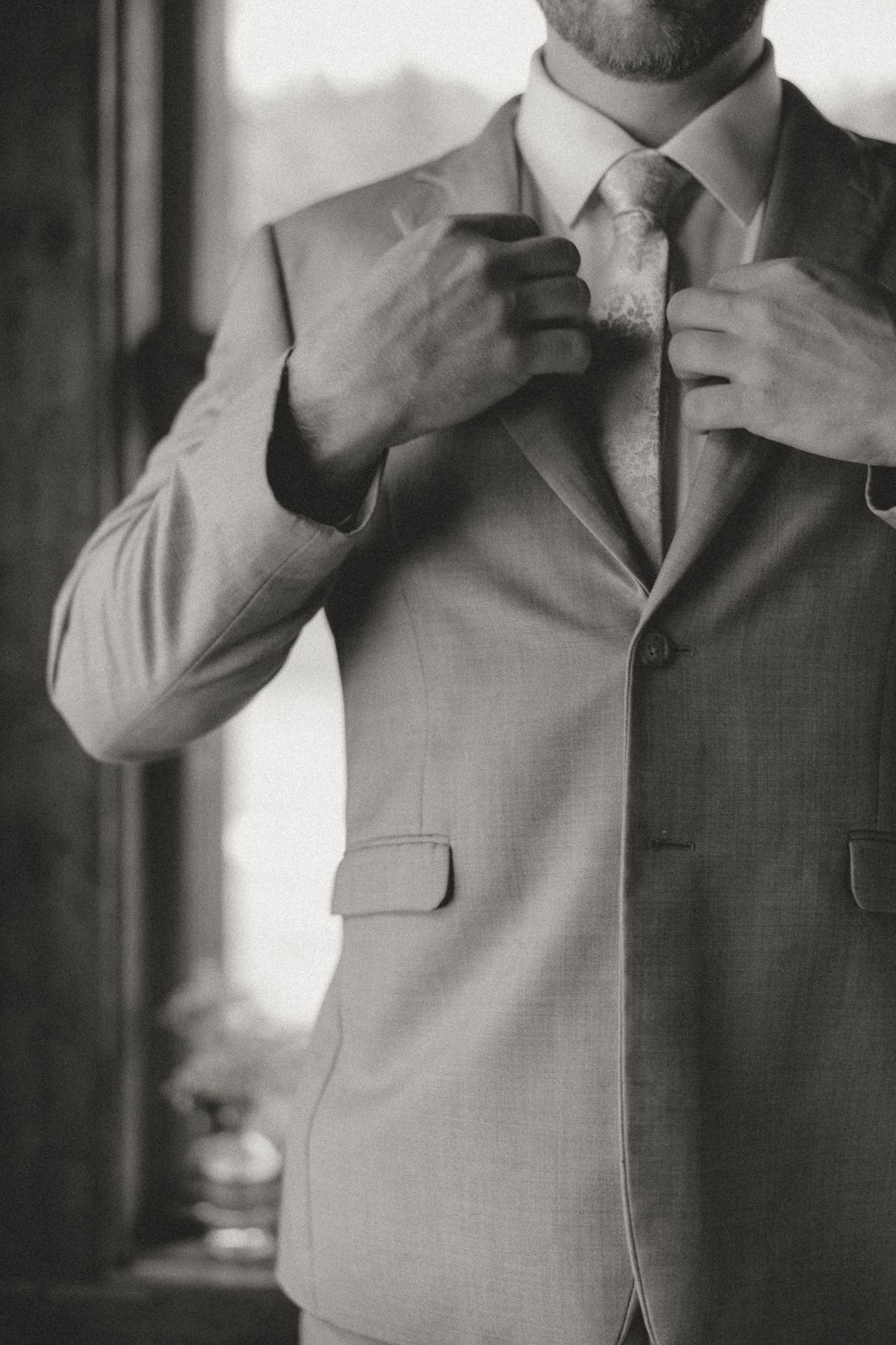 Close-up sequence of a grey suit and tie being adjusted before a formal event.