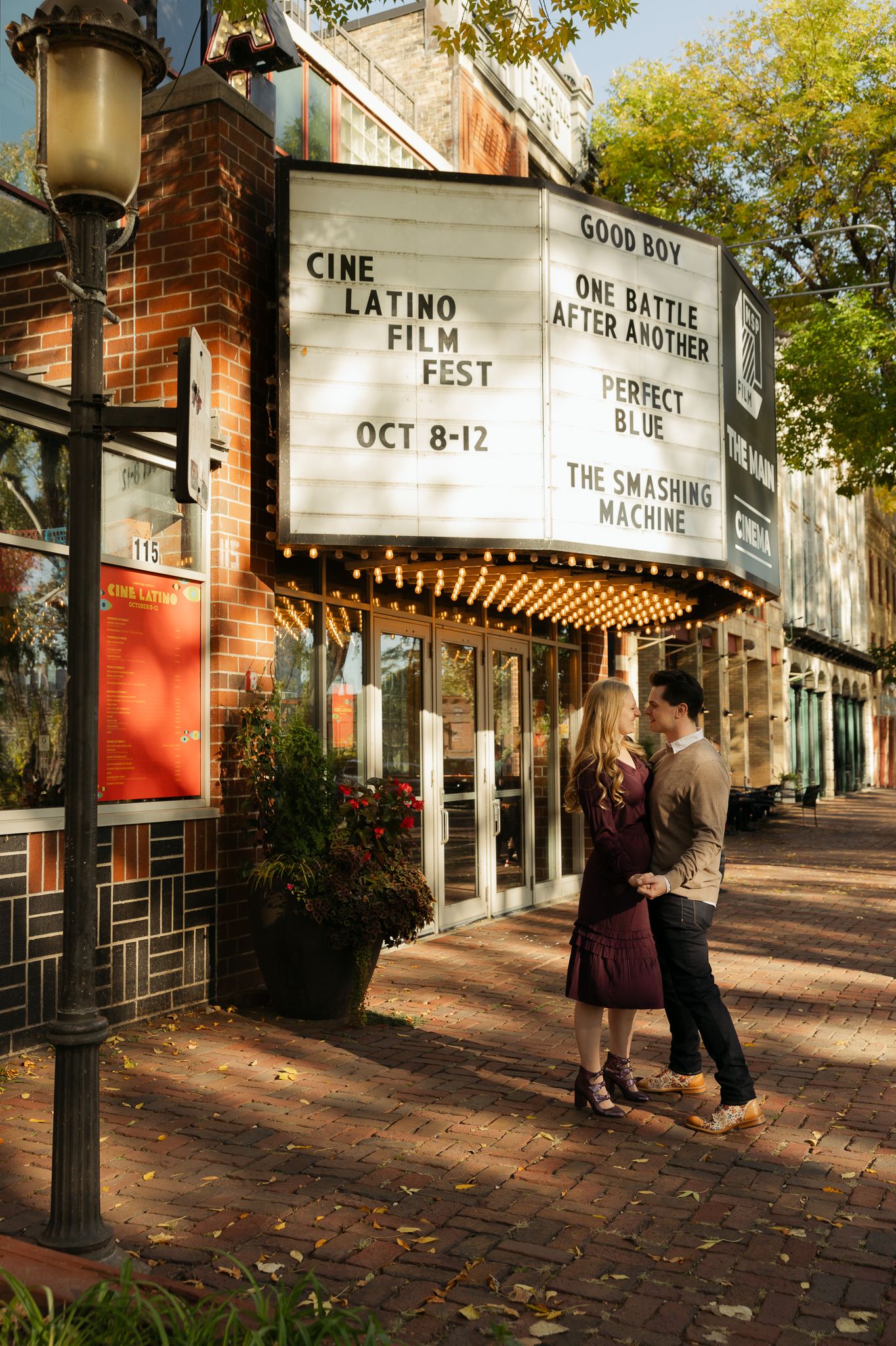 A theater exterior with movie posters and marquee signs visible on a fall afternoon.