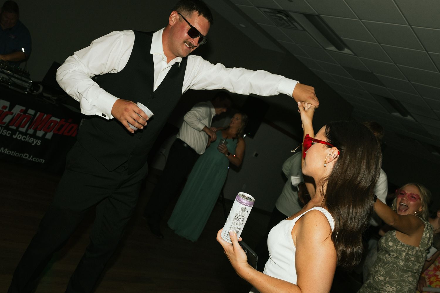 Guests dance and celebrate with drinks at a lively indoor party.