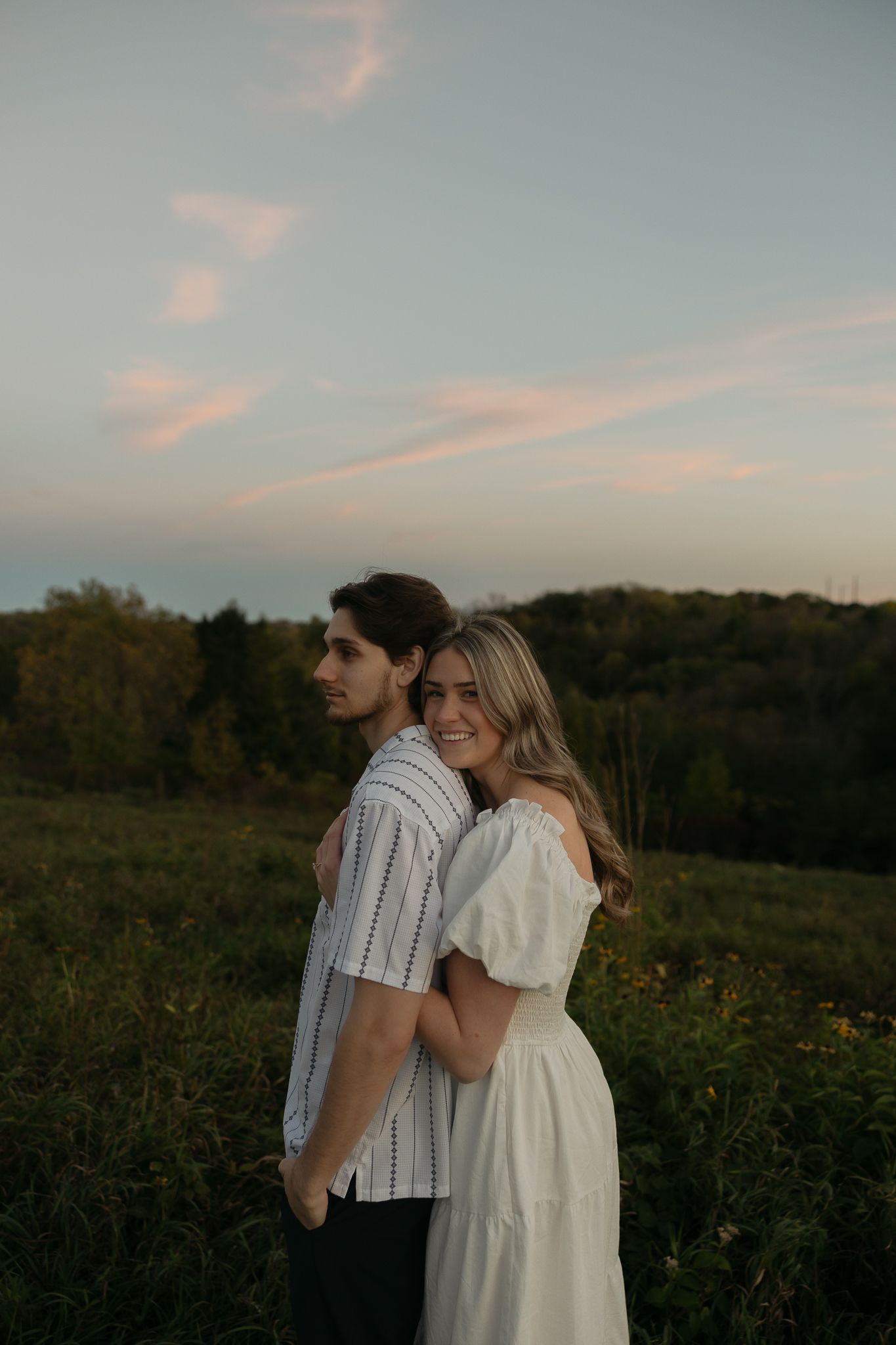 A couple embraces during golden hour in a scenic outdoor setting.