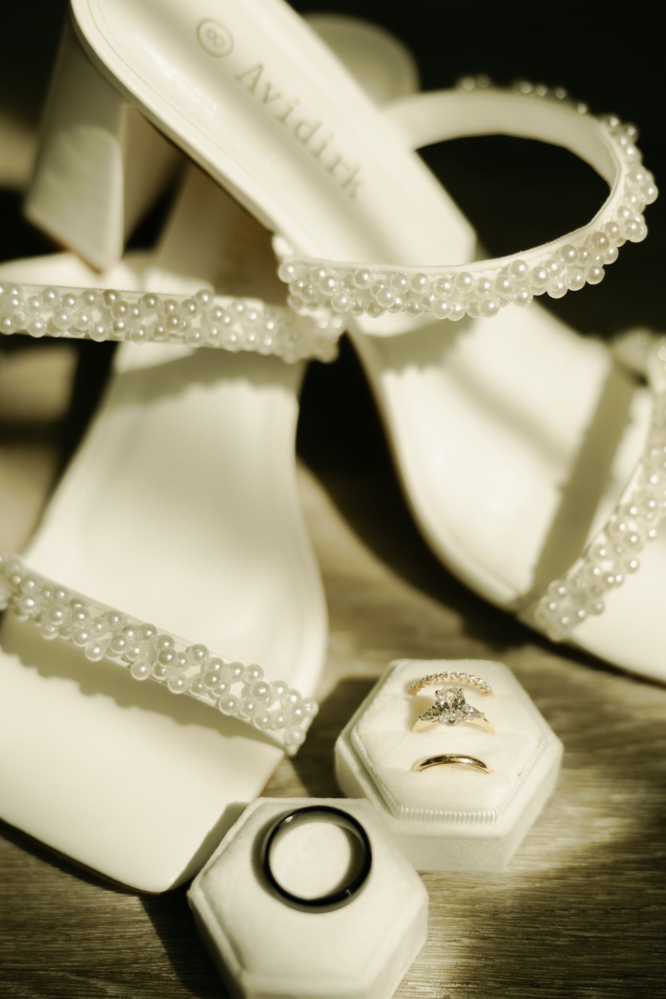 Elegant bridal shoes with pearl details and wedding rings in hexagonal boxes.