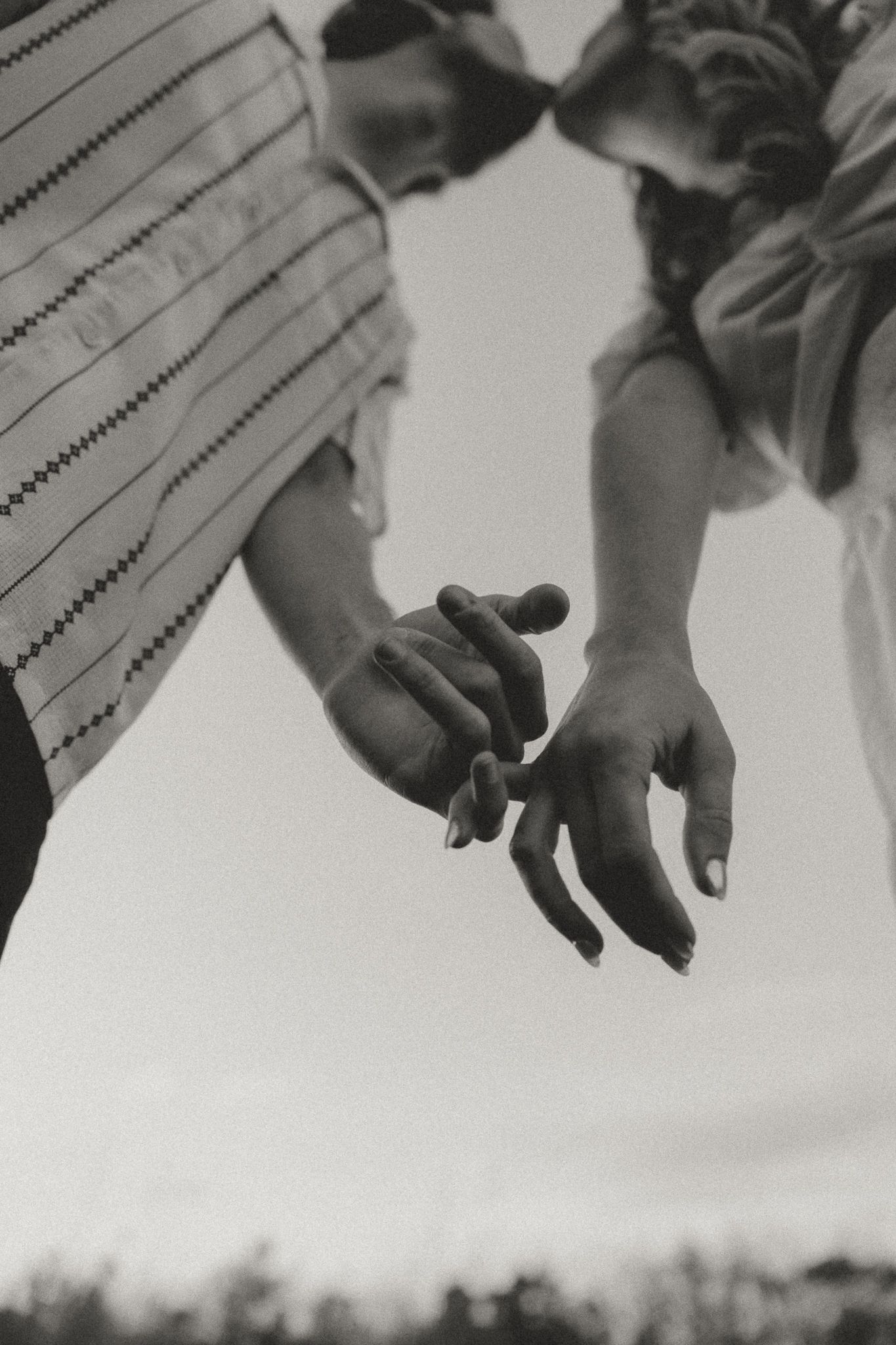 Black and white close-up of two hands reaching for each other.
