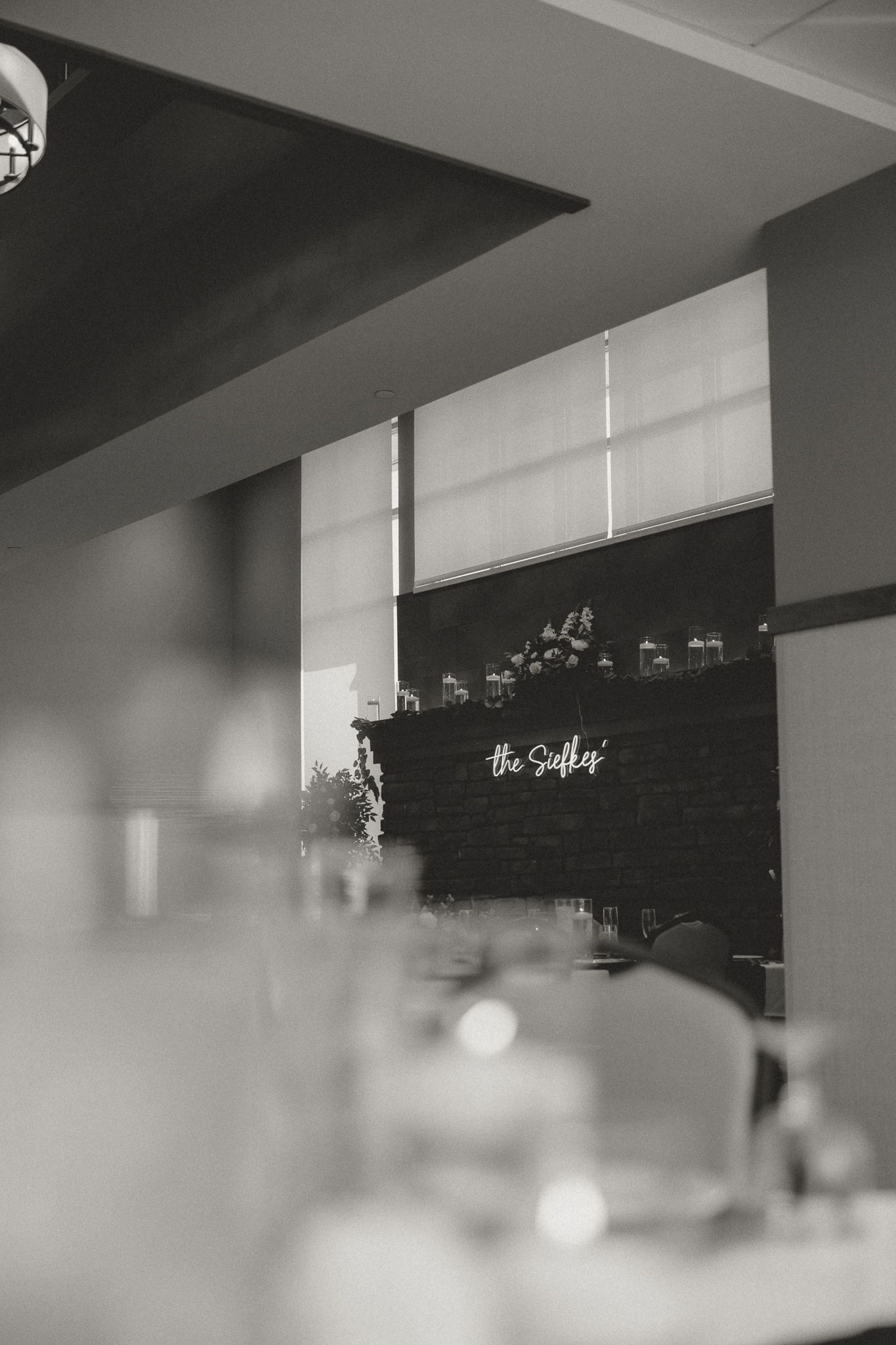Black and white interior shot of a modern venue with soft window lighting and signage.
