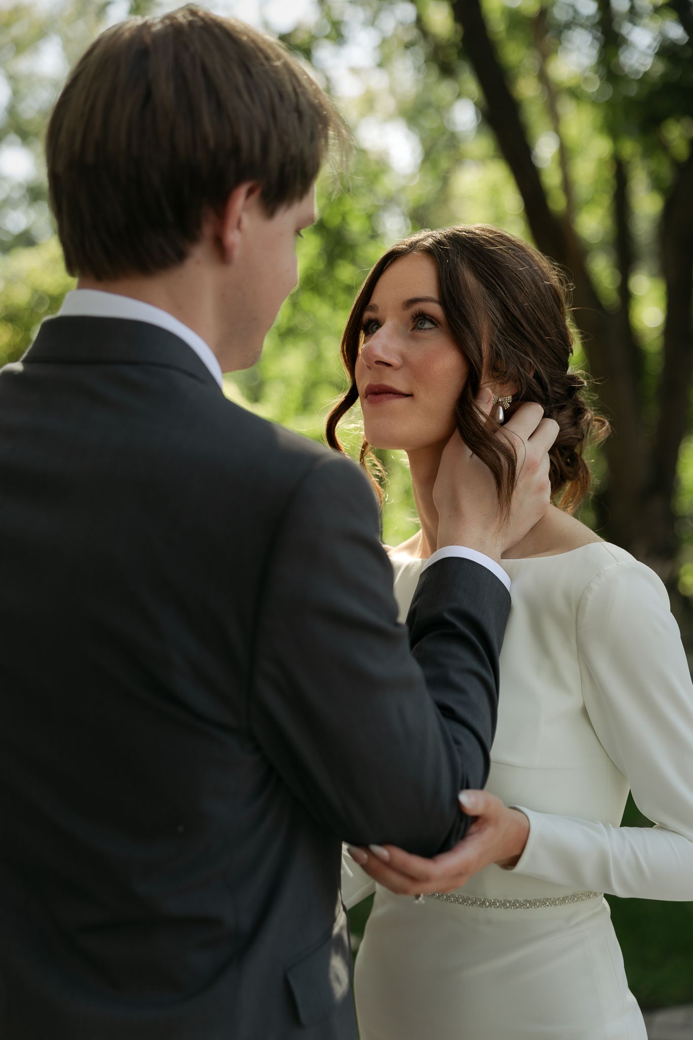 An intimate wedding moment captured in a wooded setting with natural lighting.