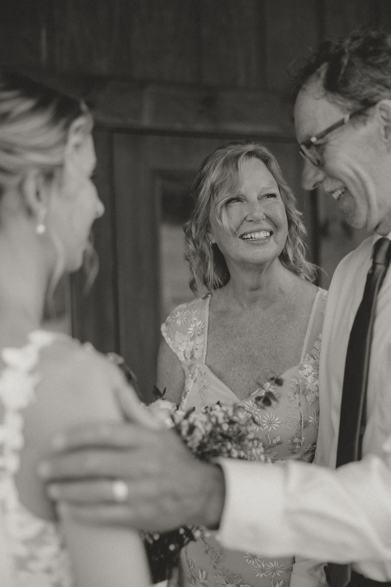 A joyful wedding moment captured in black and white showing genuine laughter and celebration.