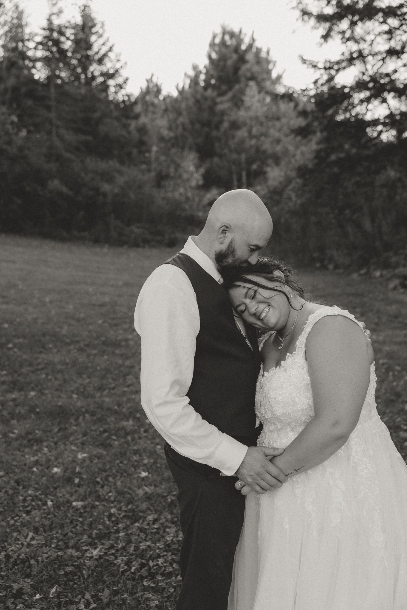 Intimate black and white portrait of a couple embracing in formal wedding attire.