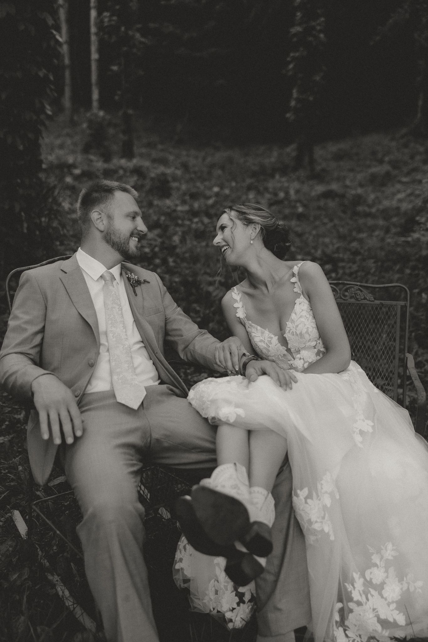 Black and white photo of newlyweds relaxing together outdoors.