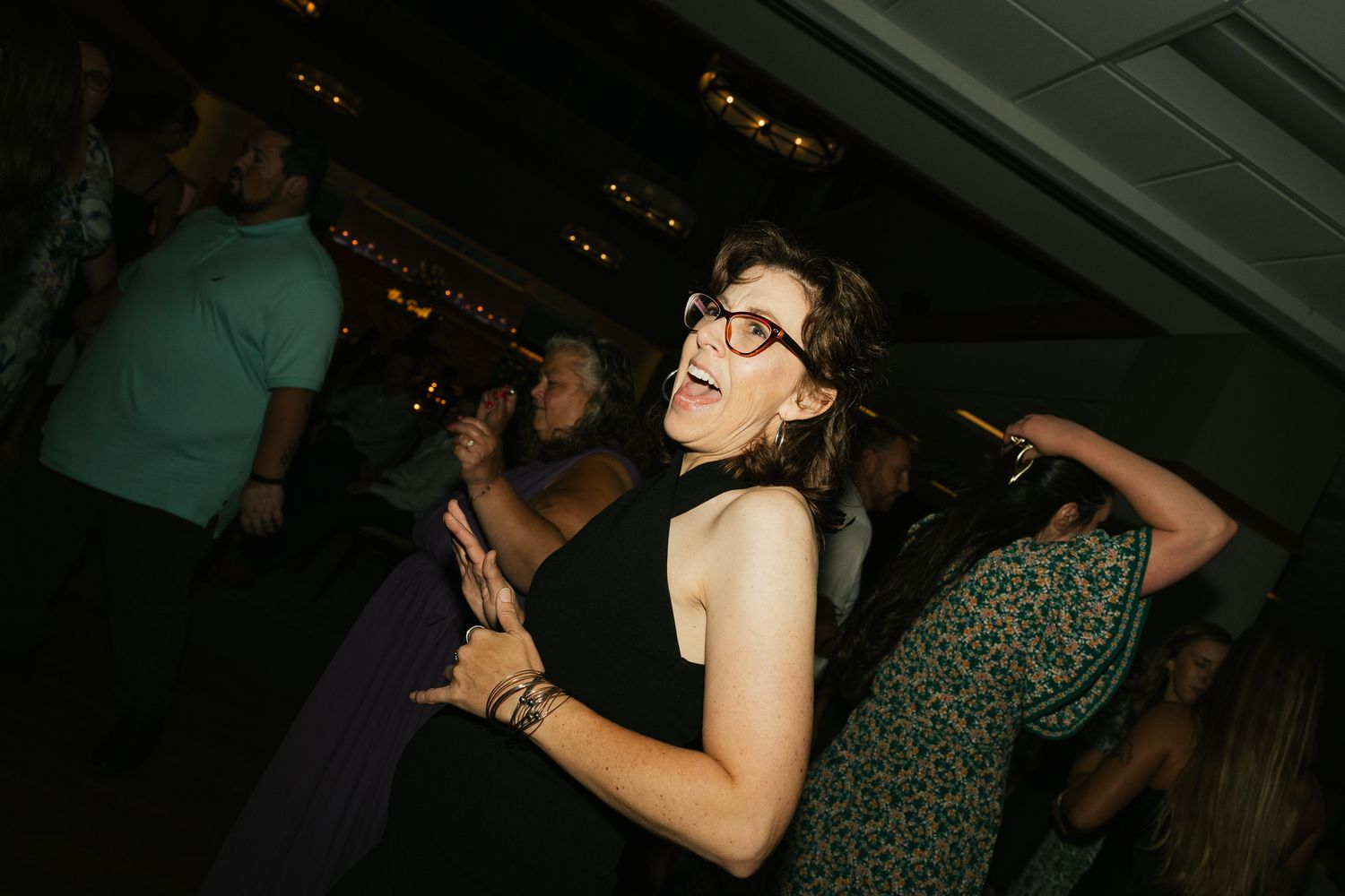 Partygoers enjoying themselves on a dark dance floor with ambient lighting.