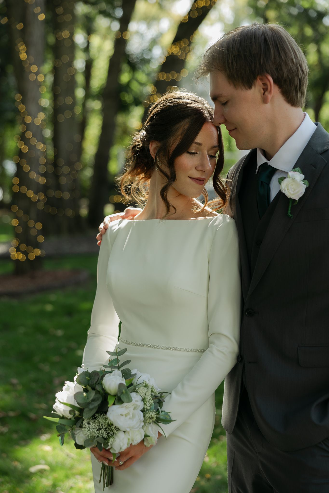 A tender wedding moment captured between a couple in an outdoor garden setting.