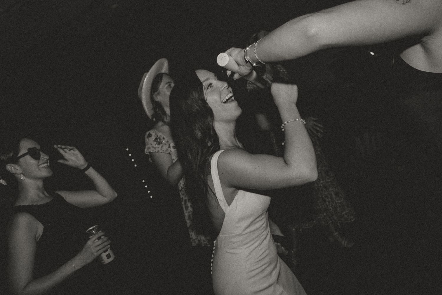 People dancing and celebrating on a dark dance floor at an event.