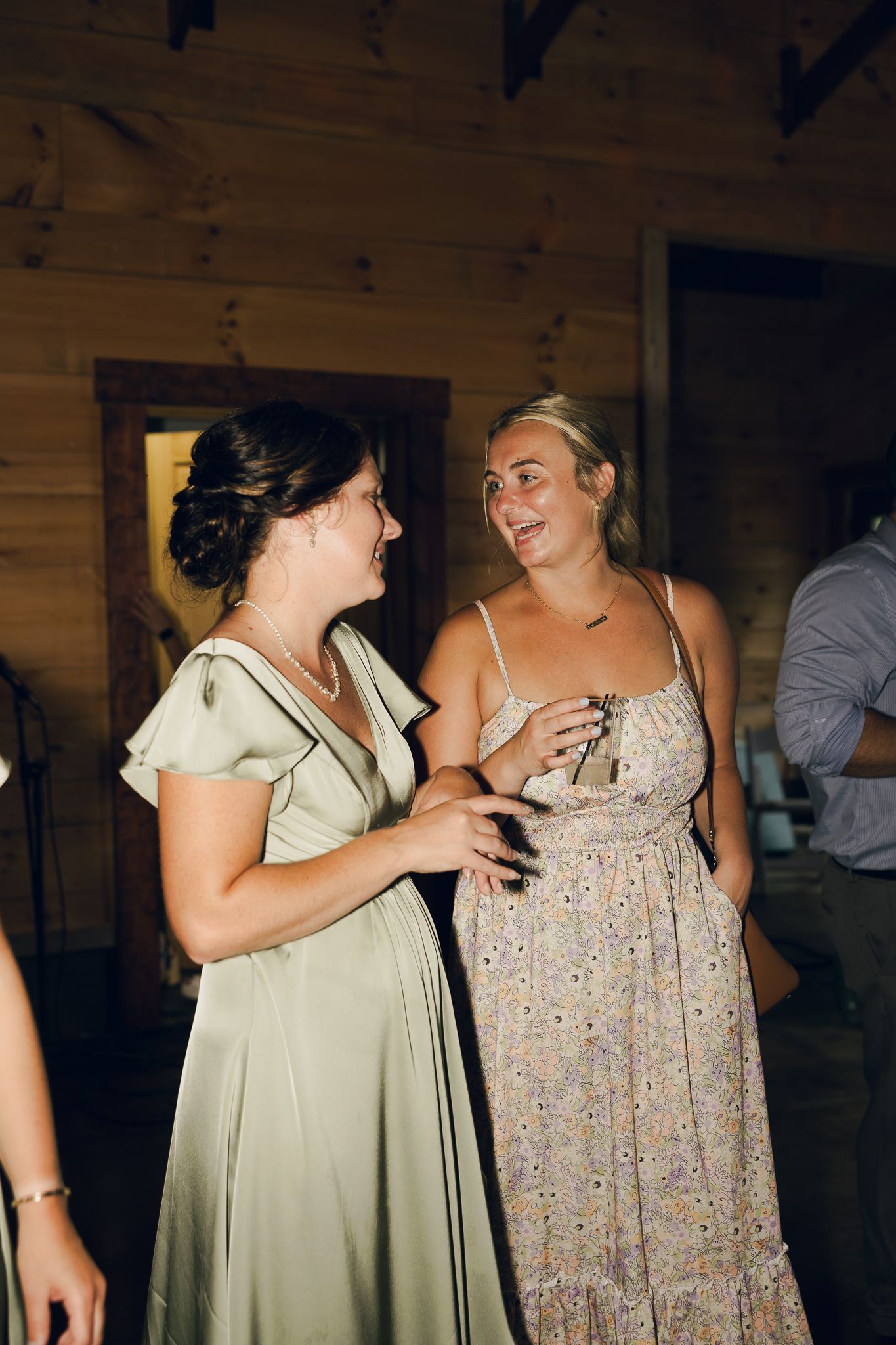 Wedding guests in casual summer dresses sharing laughs at reception.