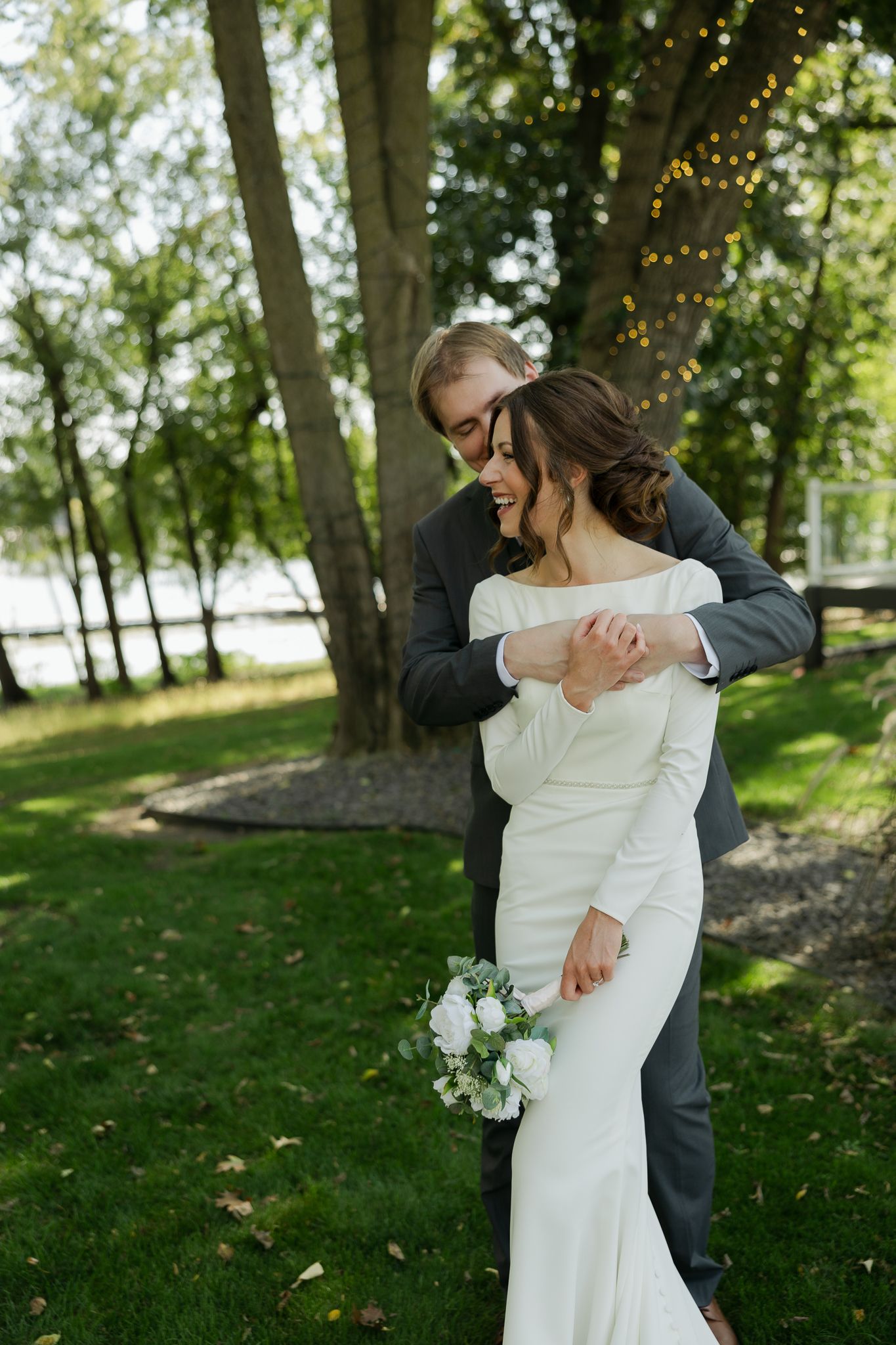 A couple shares an intimate dance moment in a sun-dappled garden setting.